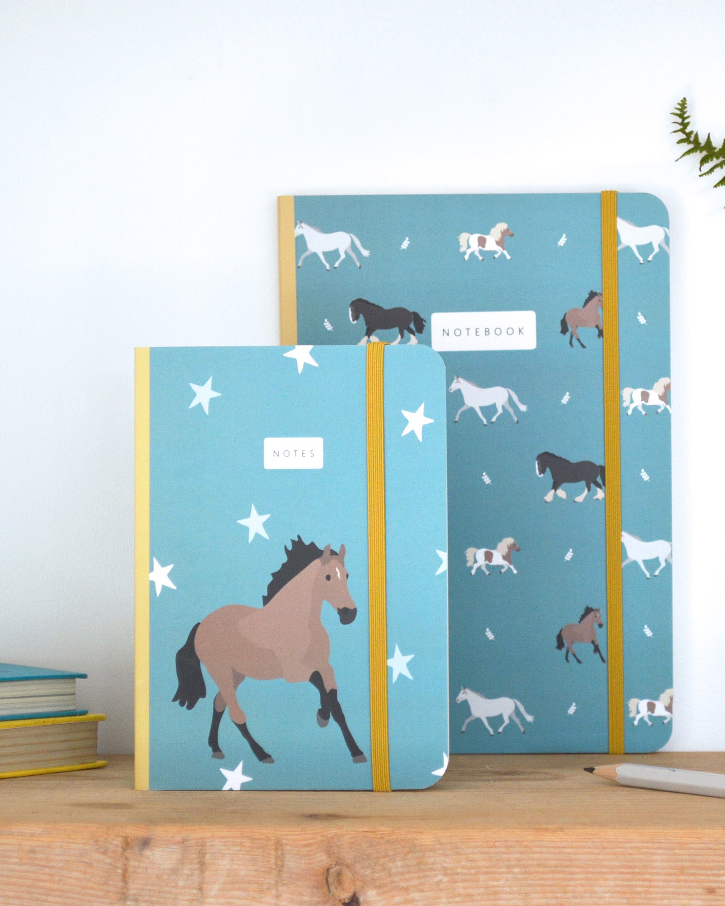 Two notebooks with horse illustrations on a wooden surface