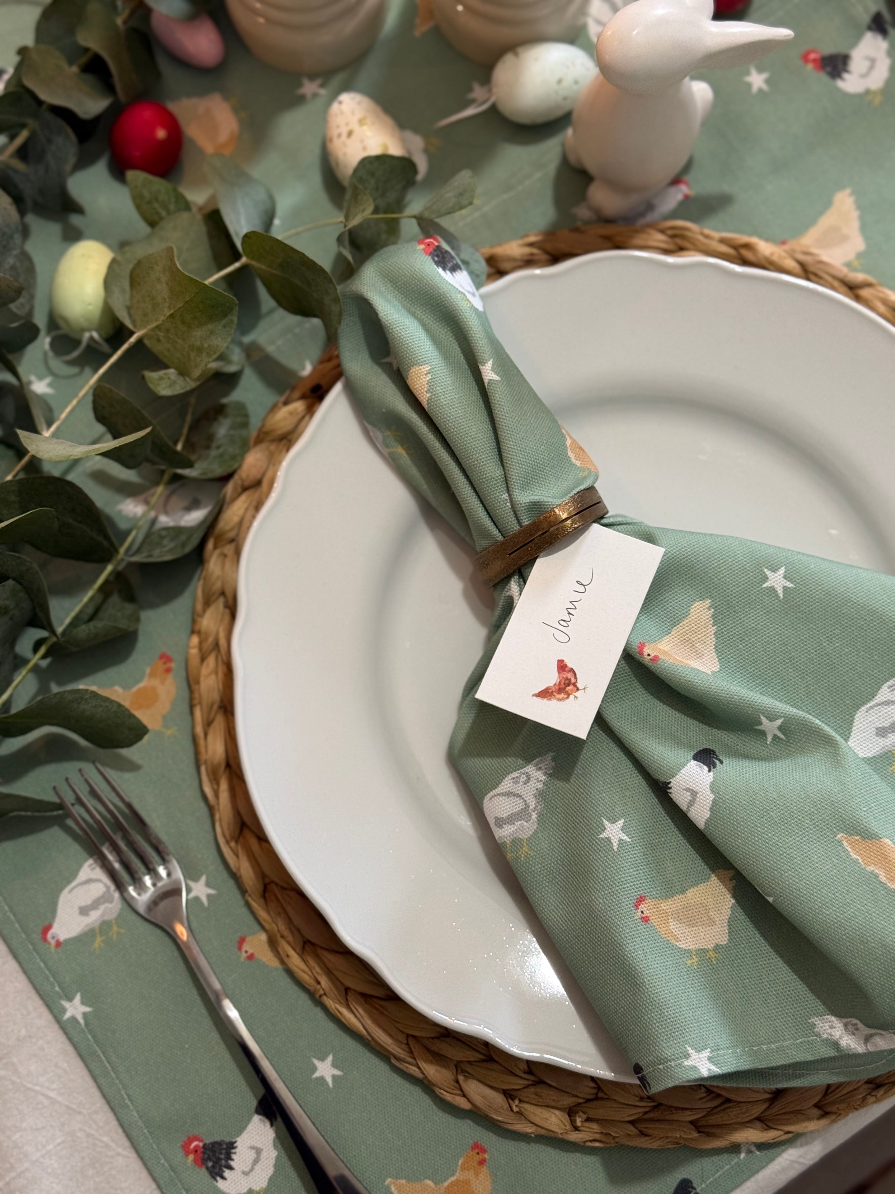Easter table setting with green chicken pattern napkin, white plate, and decorative elements.