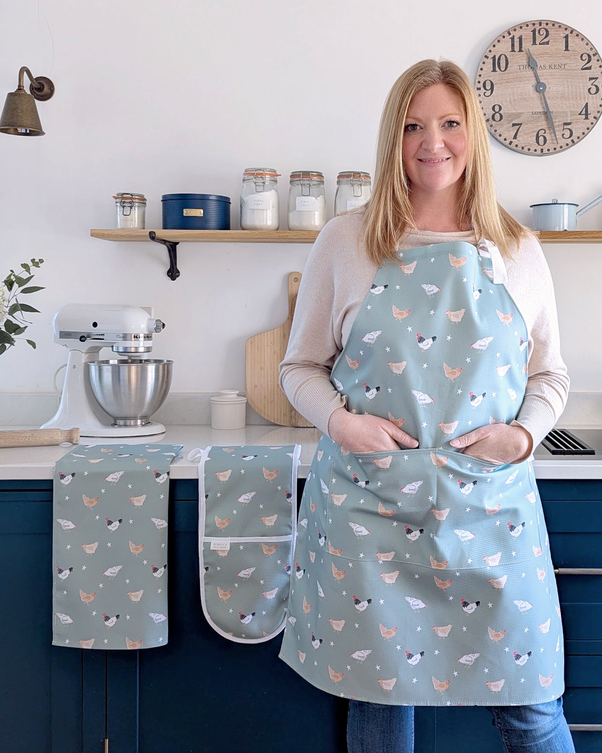 Rebecca Pitcher wearing a matching chicken apron and kitchen linens in a kitchen setting