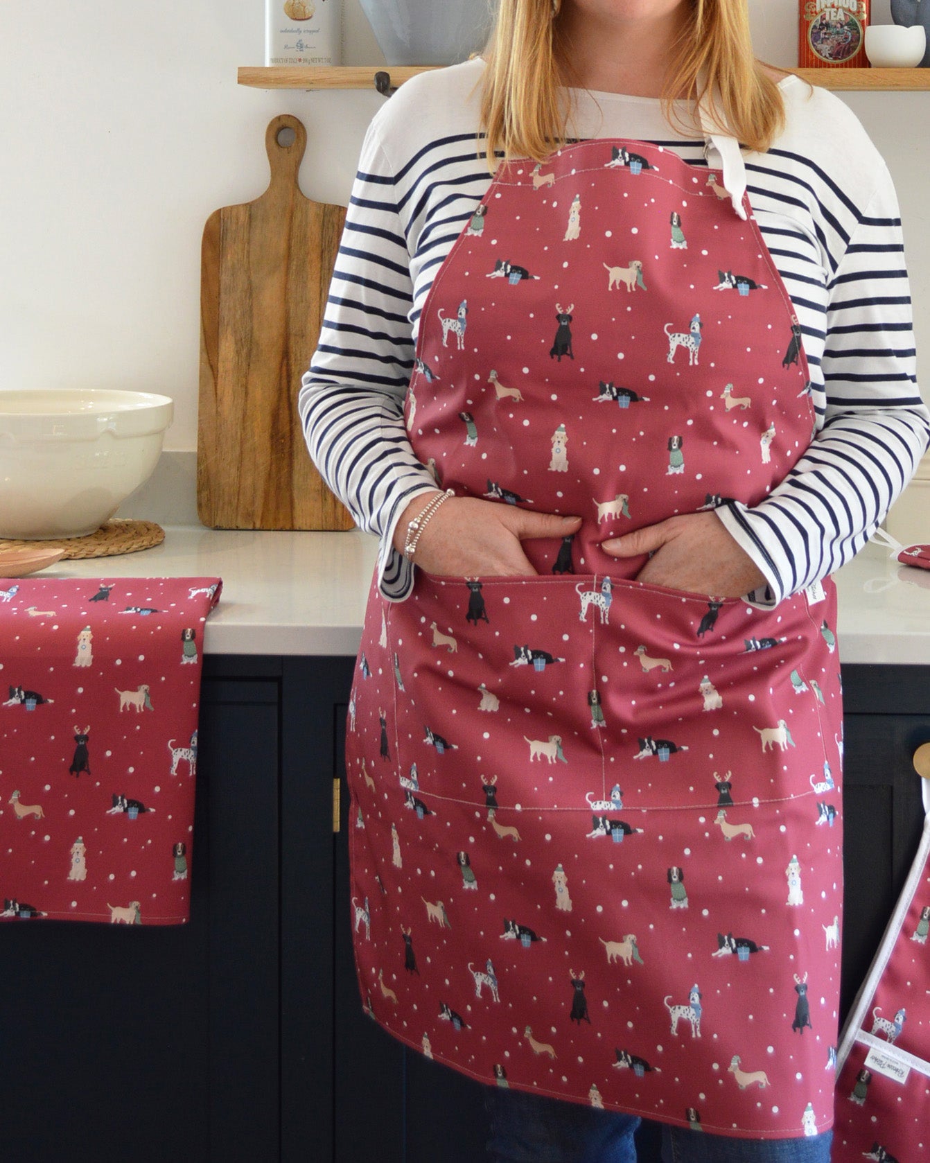 Person wearing a red apron with Christmasdog pattern in a kitchen setting