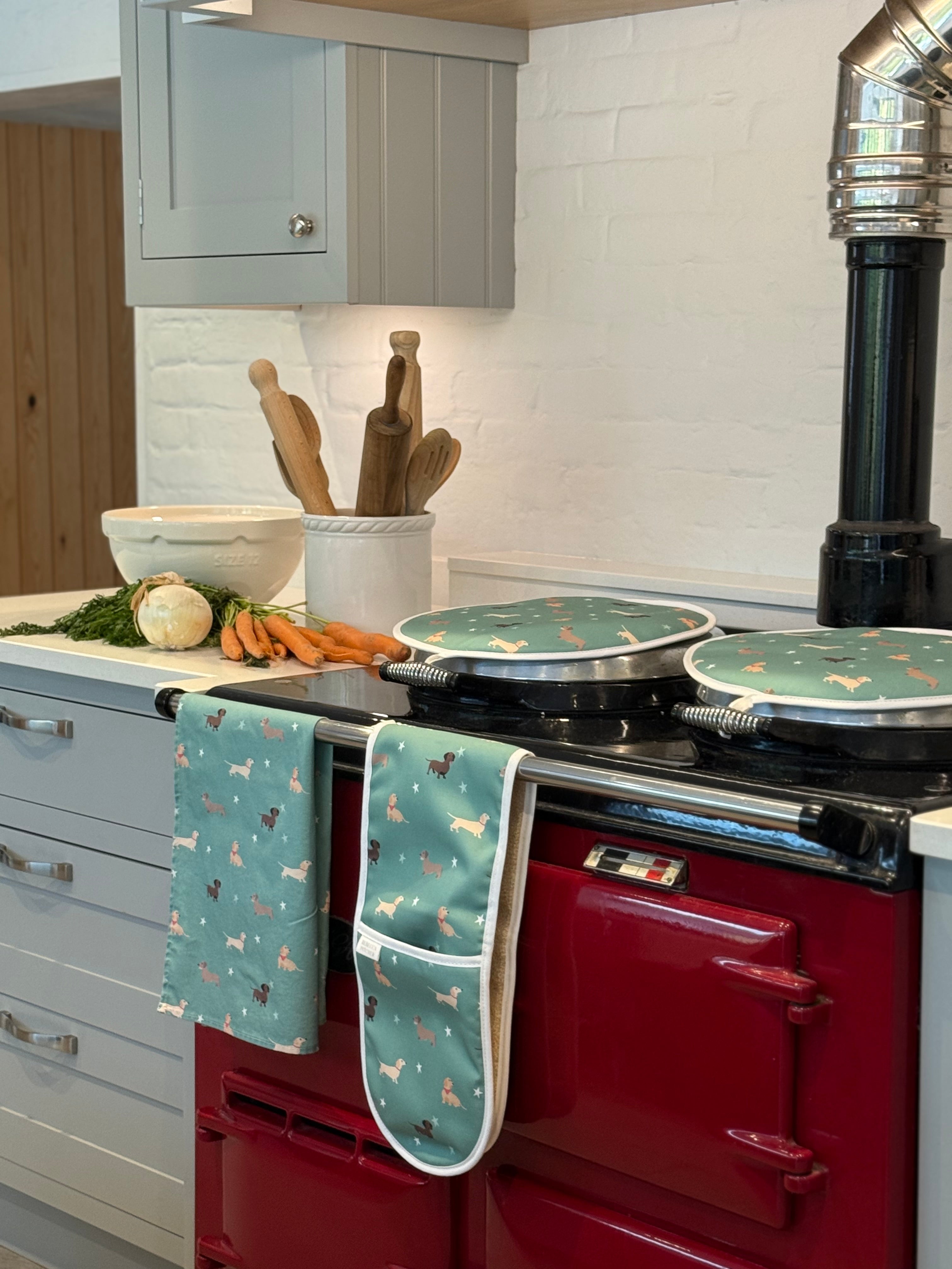 Green Dachshund design hob covers, oven gloves and tea towel on a range cooker in a country kitchen