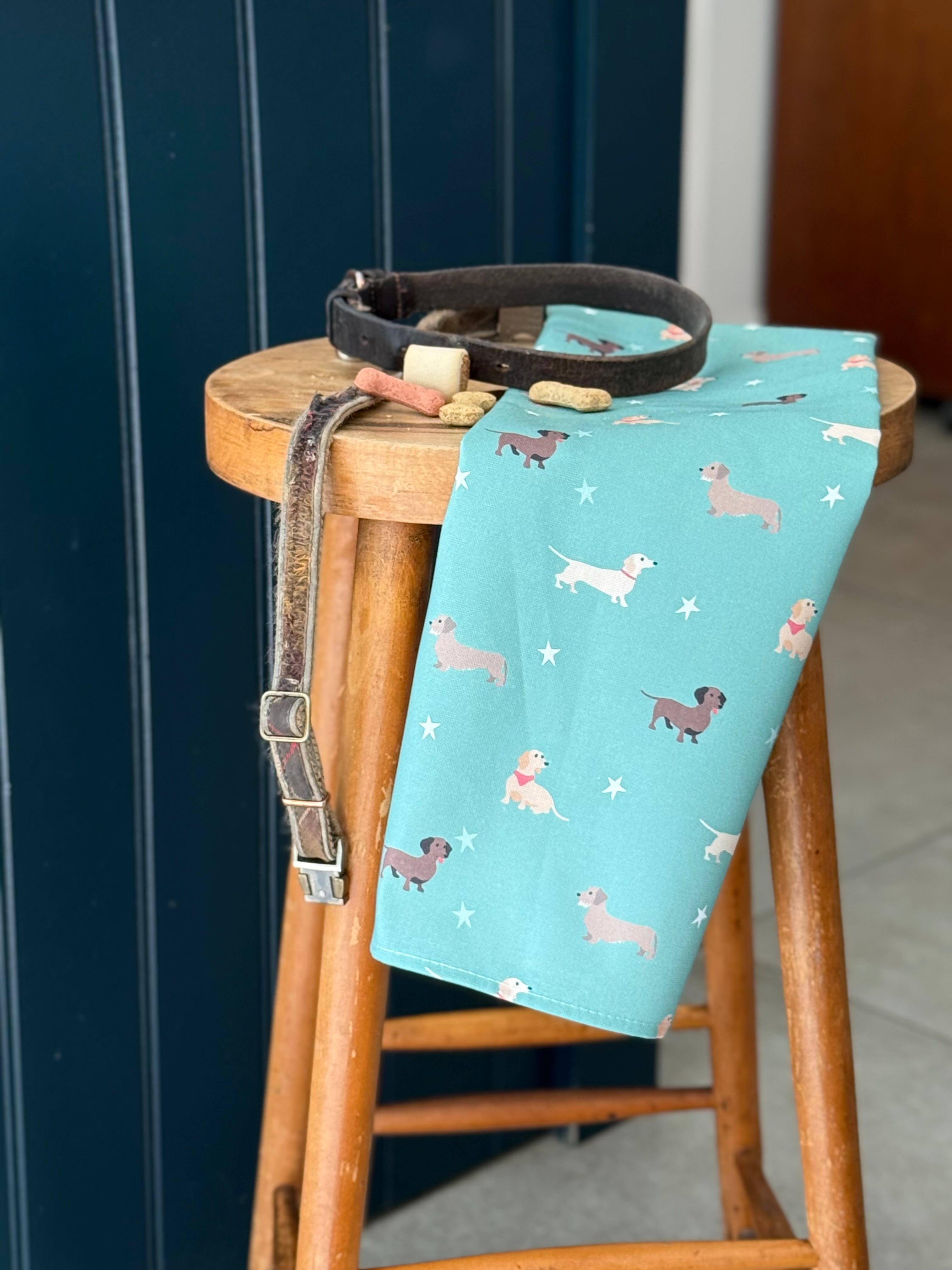 Green tea towel with dachshund dog pattern on a wooden stool against a dark blue kitchen island