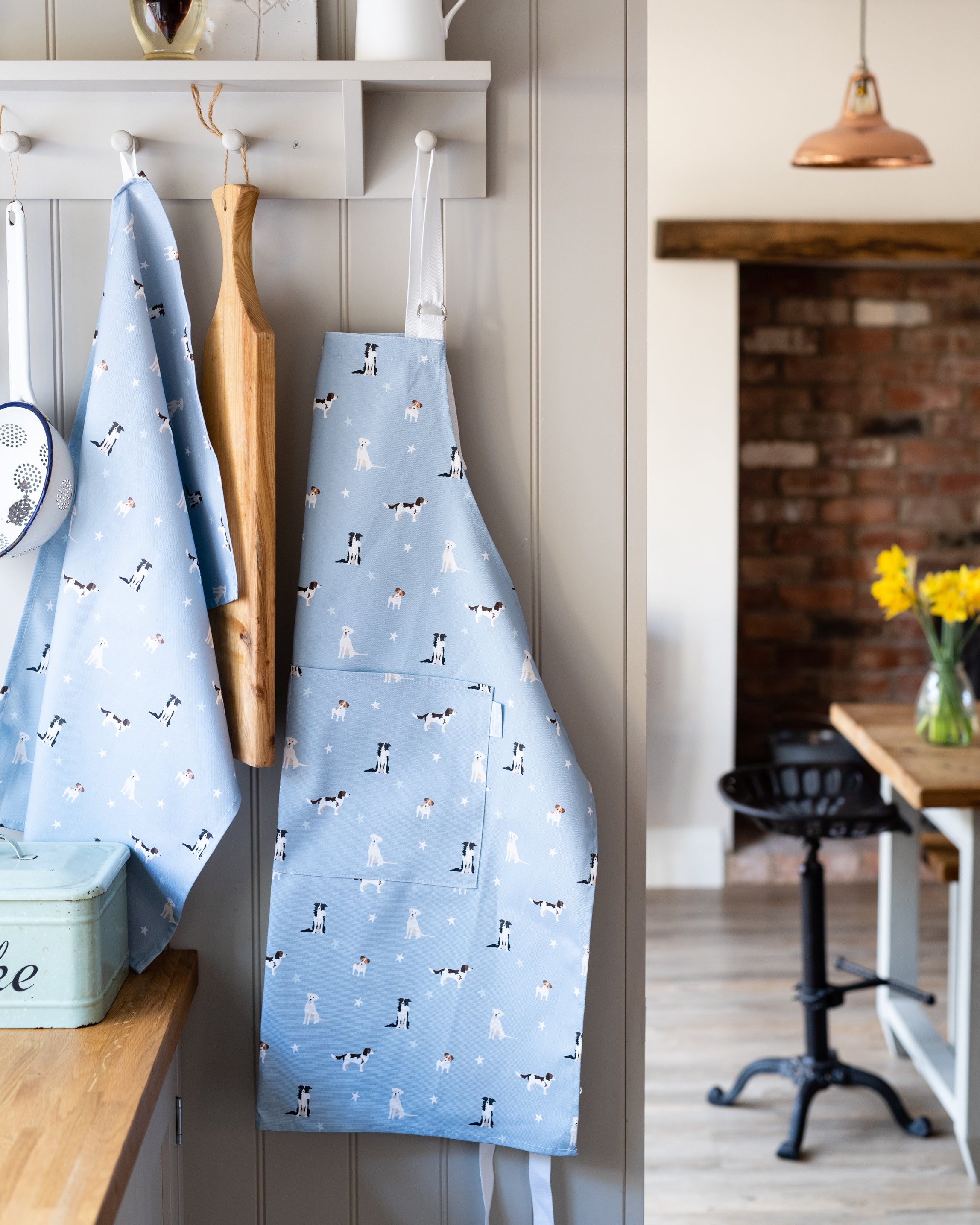 Blue apron with dog pattern hanging on a hook in a kitchen.