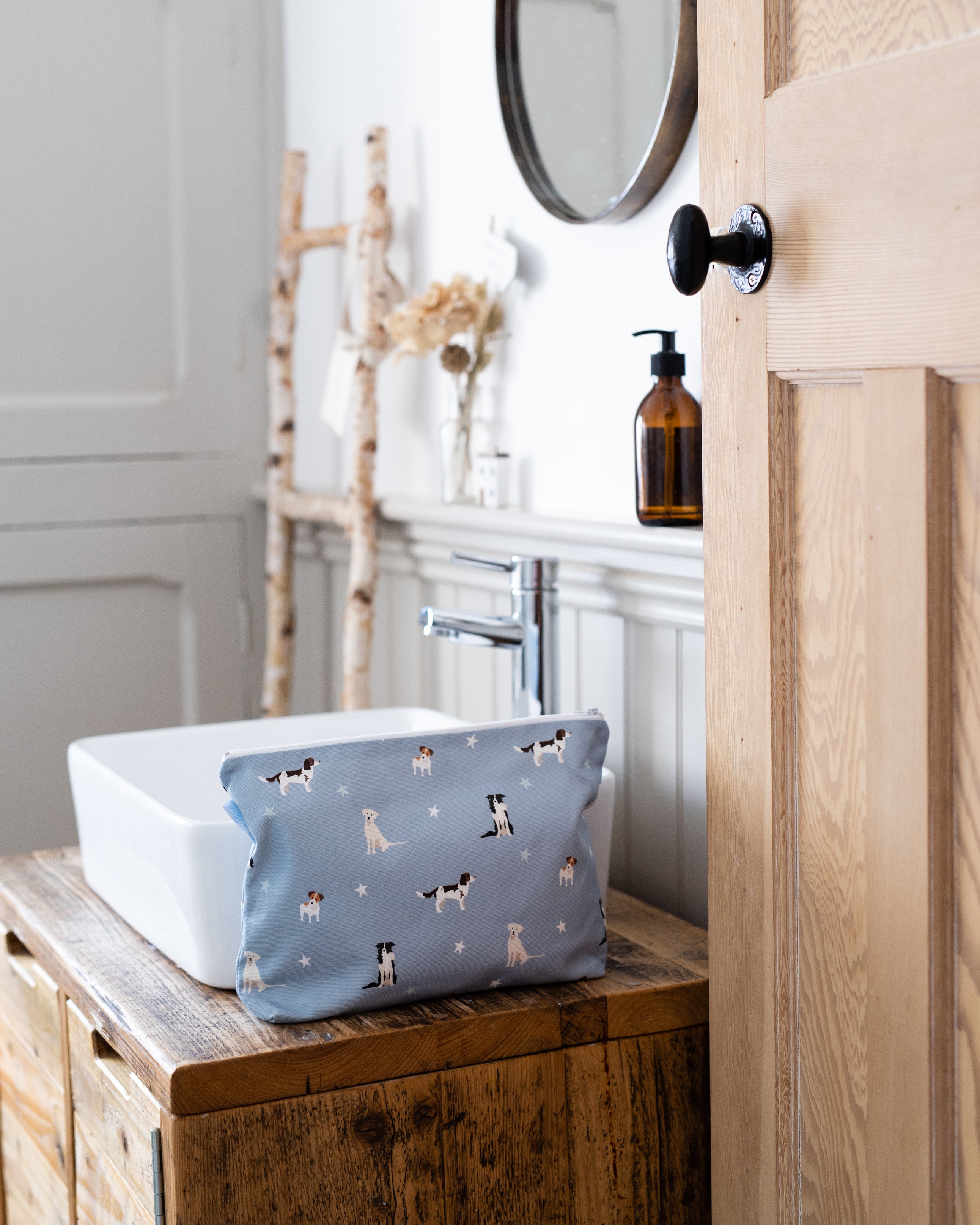 Bathroom with a wooden vanity, white sink, and blue washbag with dog pattern.