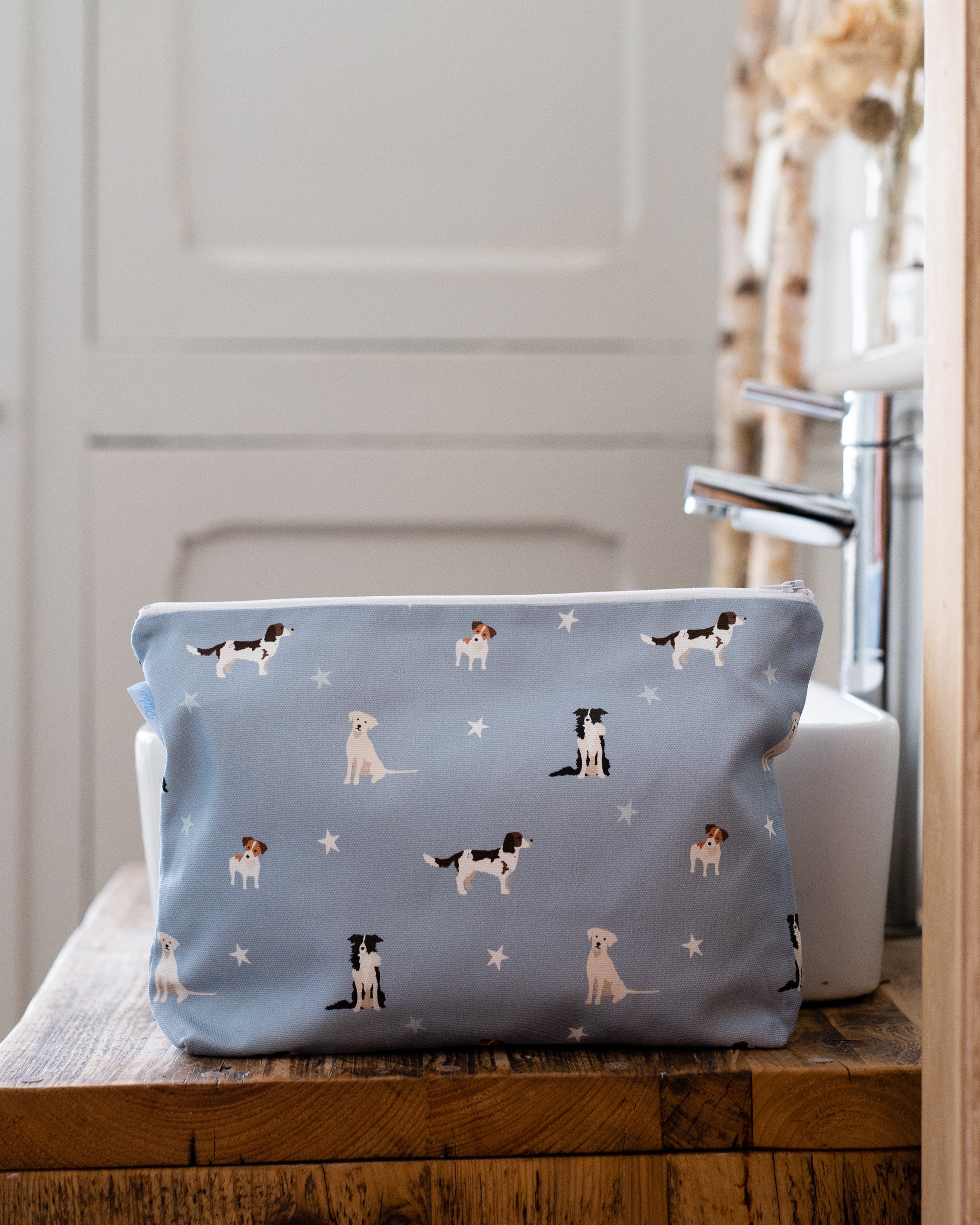 Blue toiletry bag with dog pattern on a wooden surface