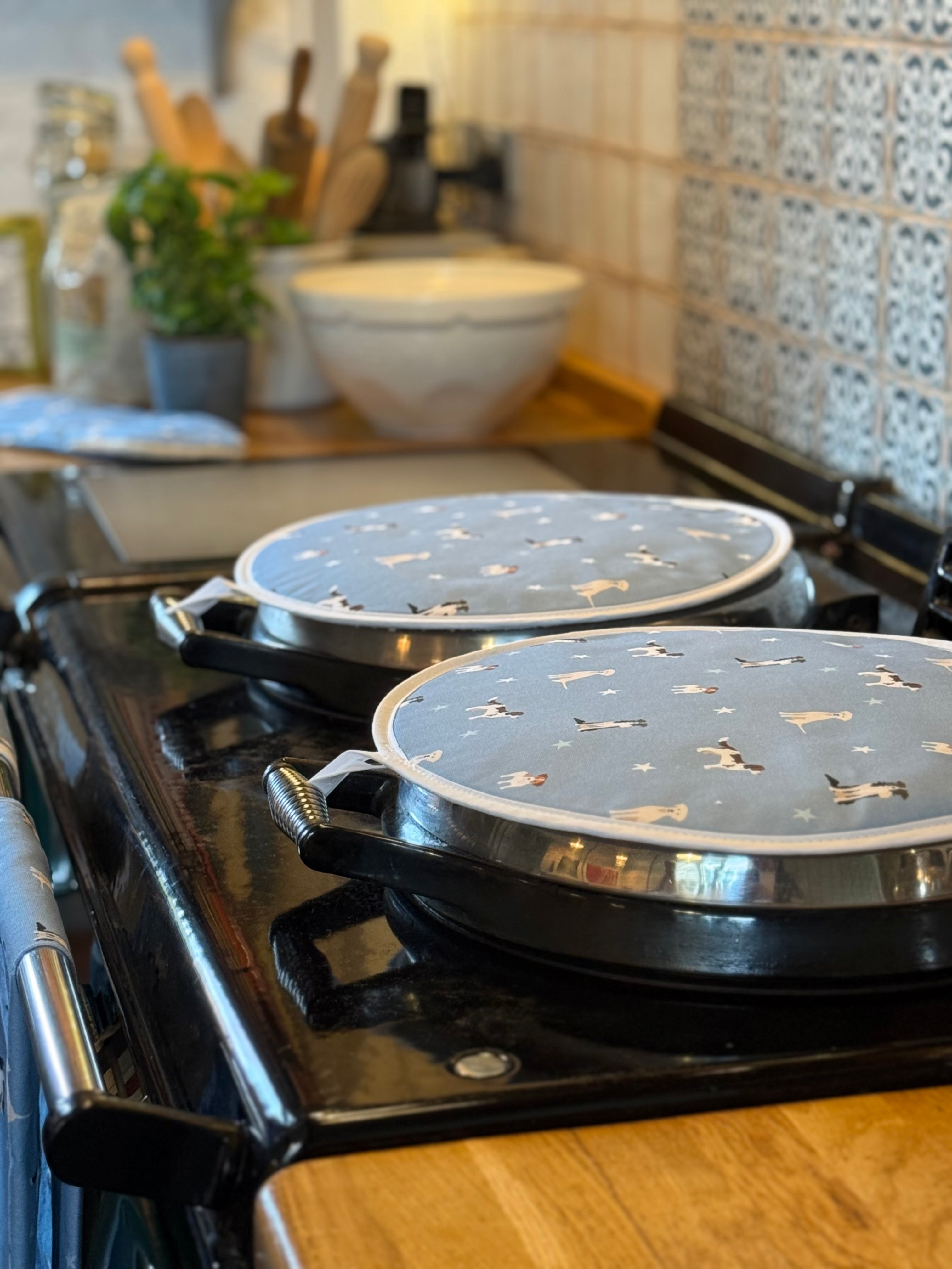 Two round hob covers with dogs pattern on a stovetop with a kitchen background