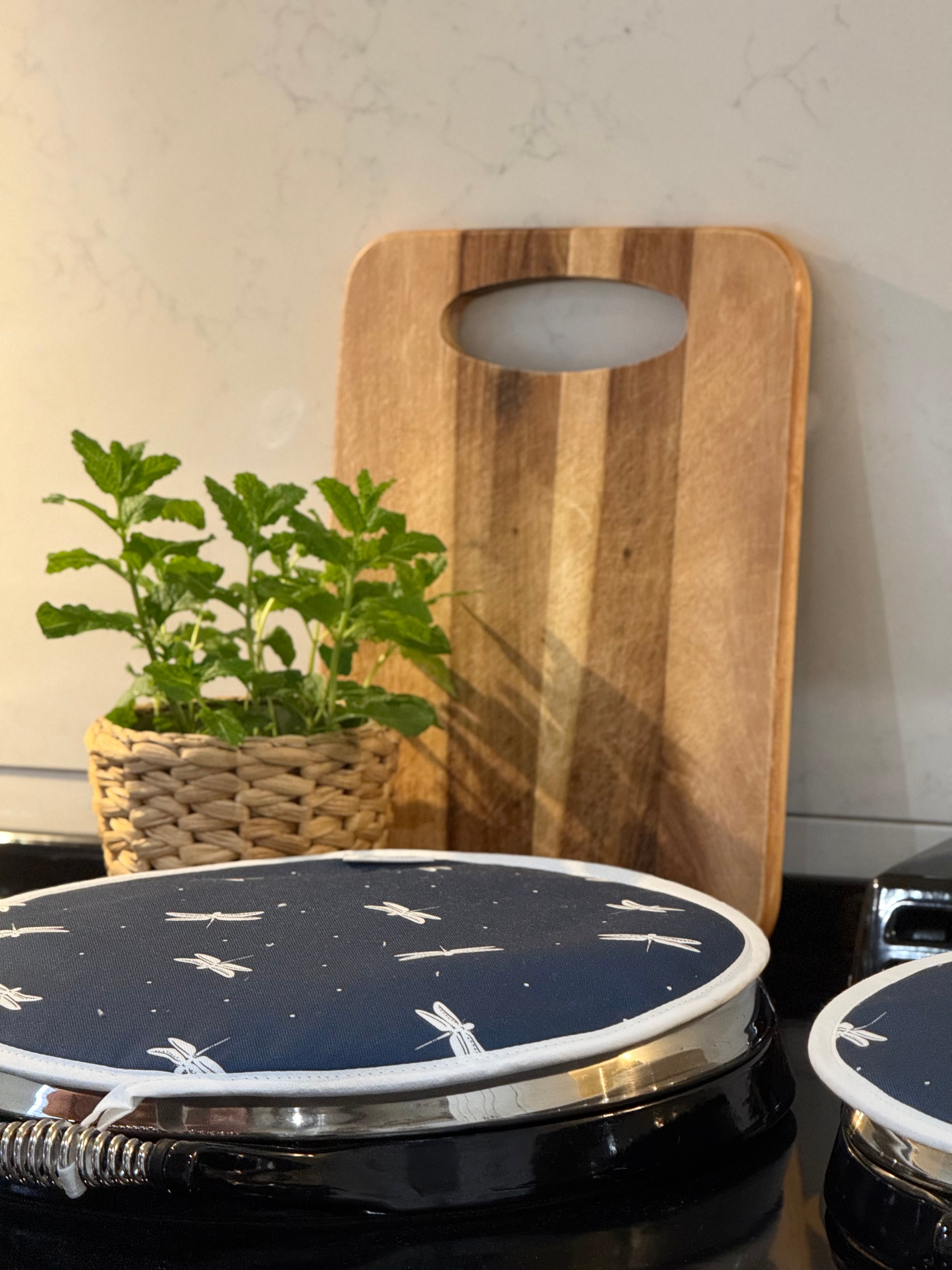 Navy Dragonfly pattern hob cover with a wooden chopping board and herb
