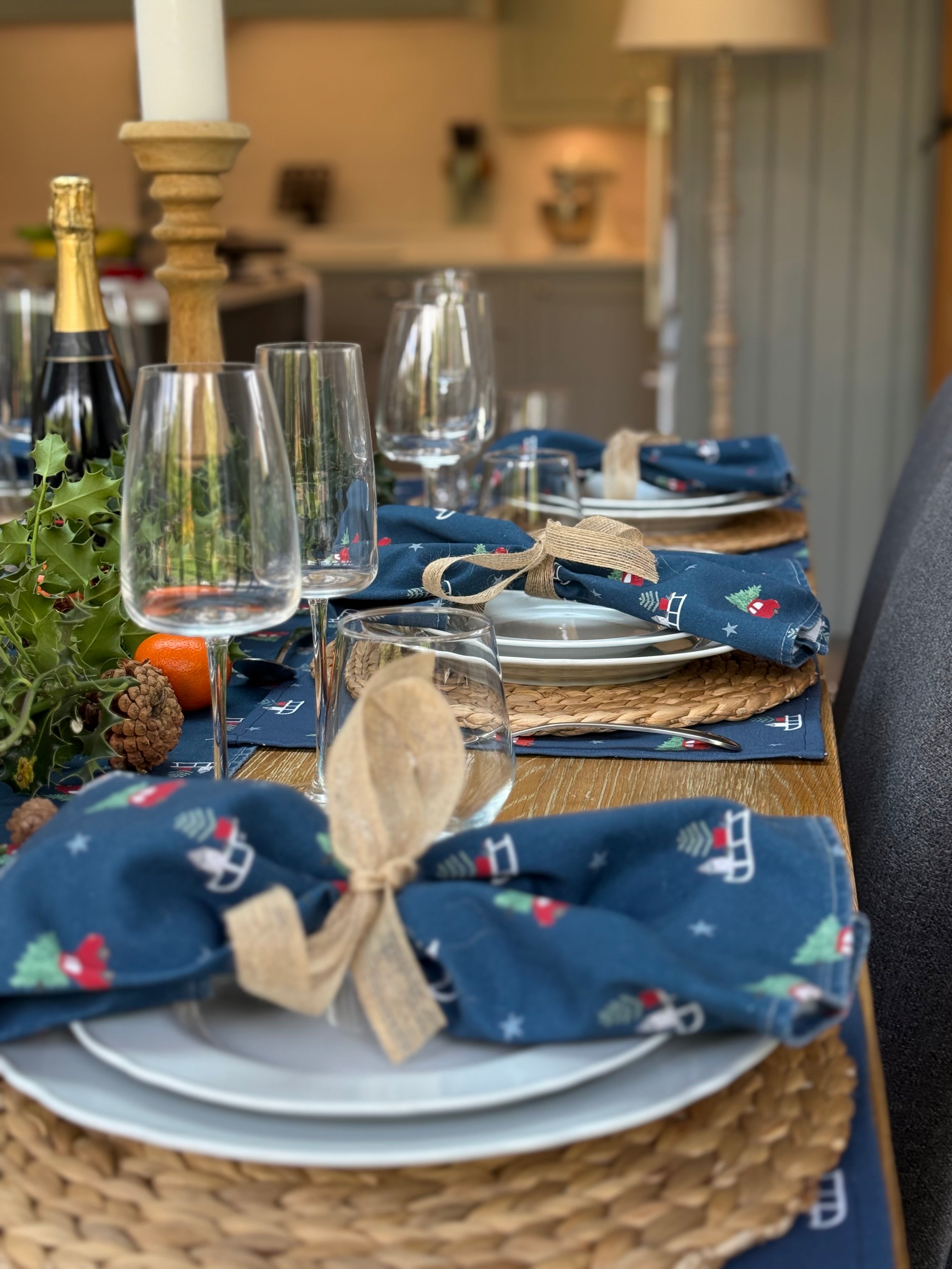 Dining table set with Christmas-themed napkins and glasses.
