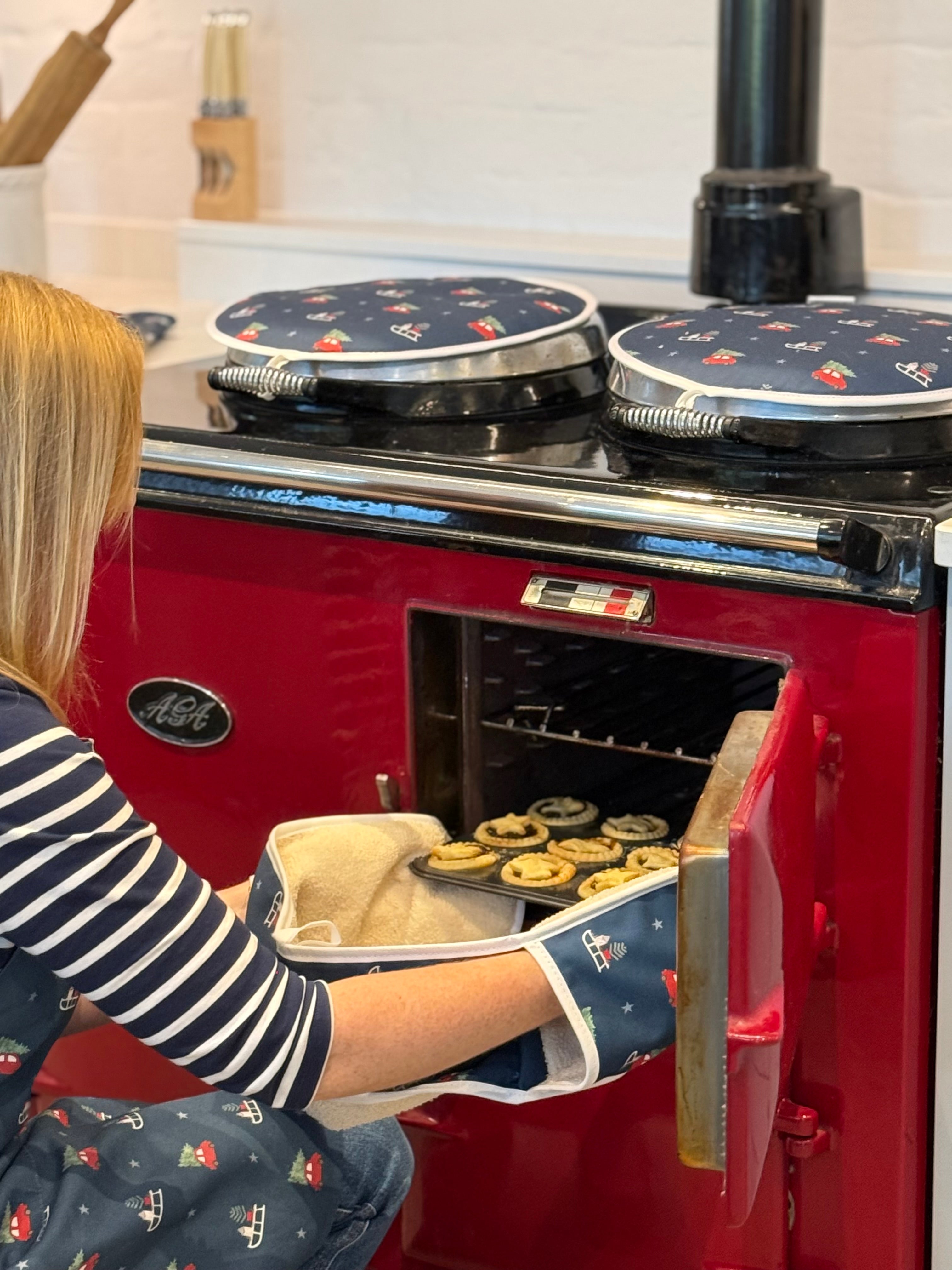 Navy Christmas design hob covers on a red aga with person taking baking out of the oven