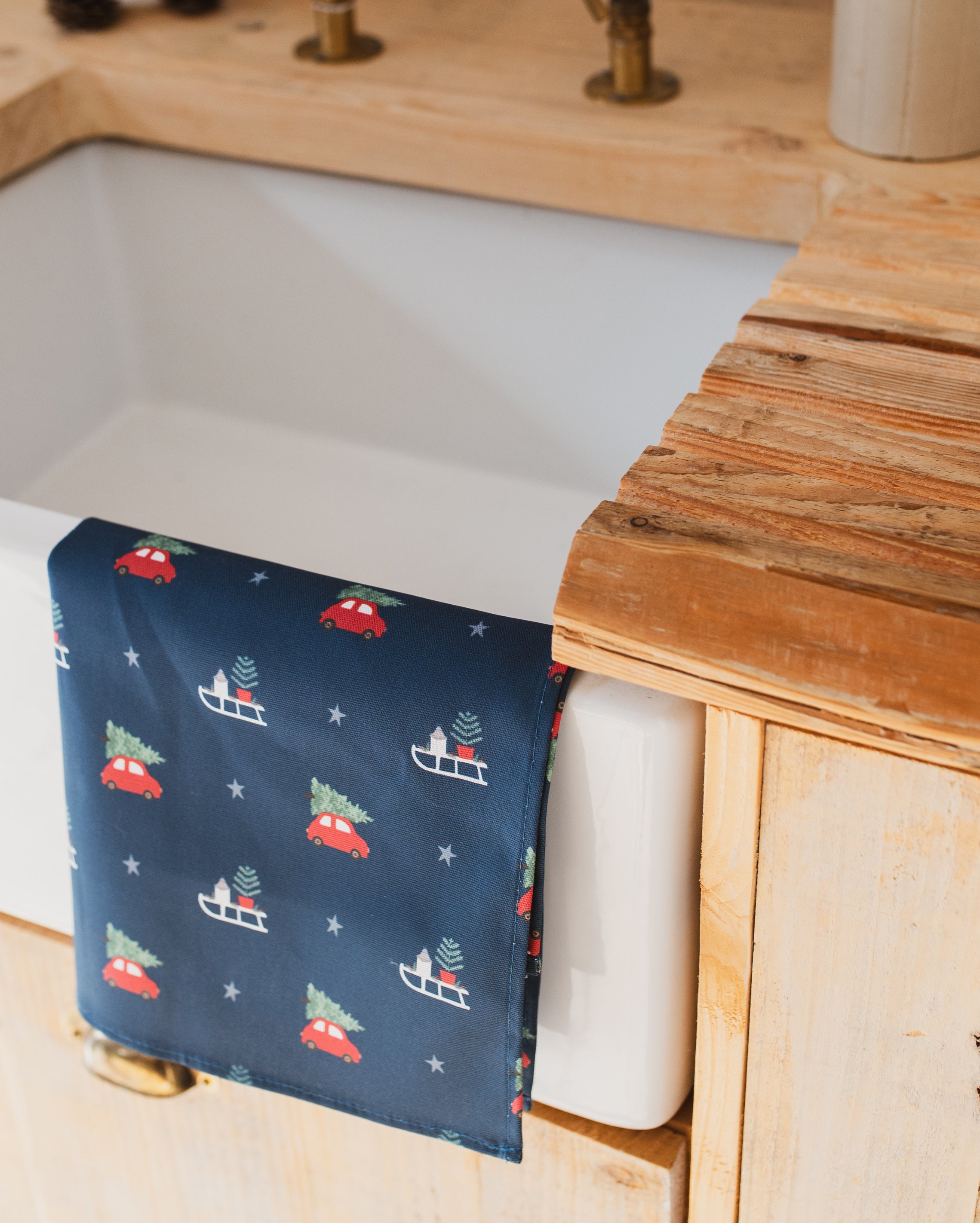 Christmas design tea towel on a sink with wooden countertop.
