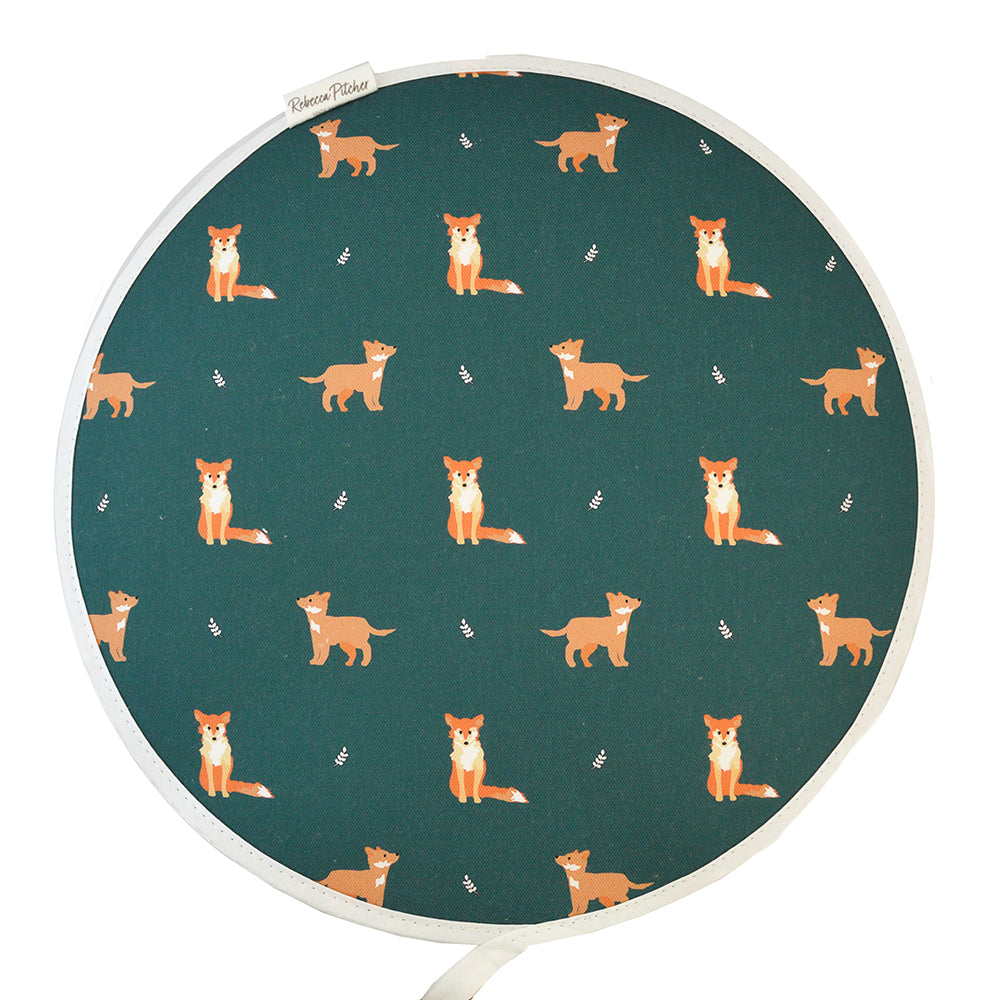 A dark green circular hob cover with a pattern of fox motifs in the center.