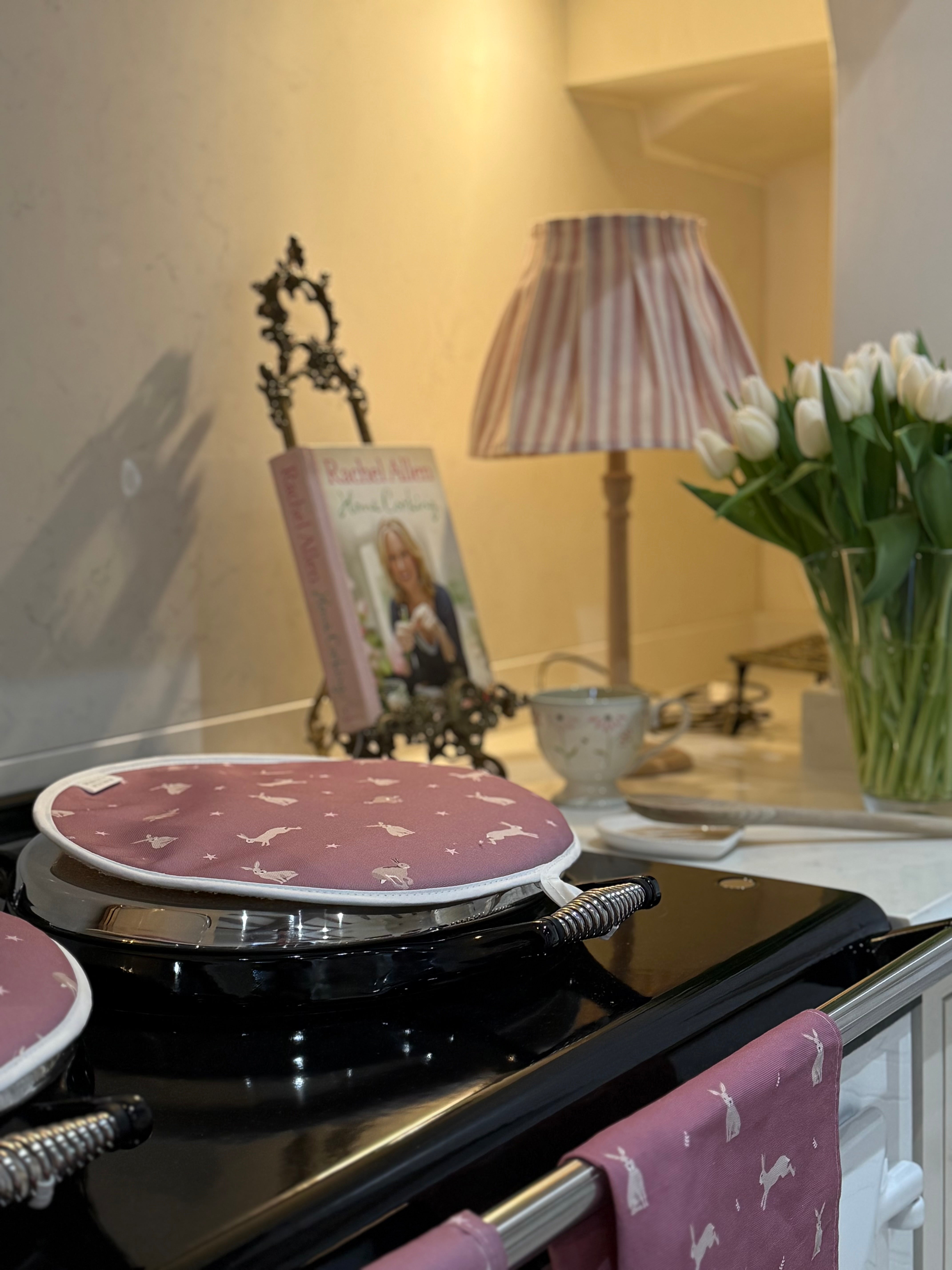Pink Hare design hob cover on a kitchen stove with lampshade in background