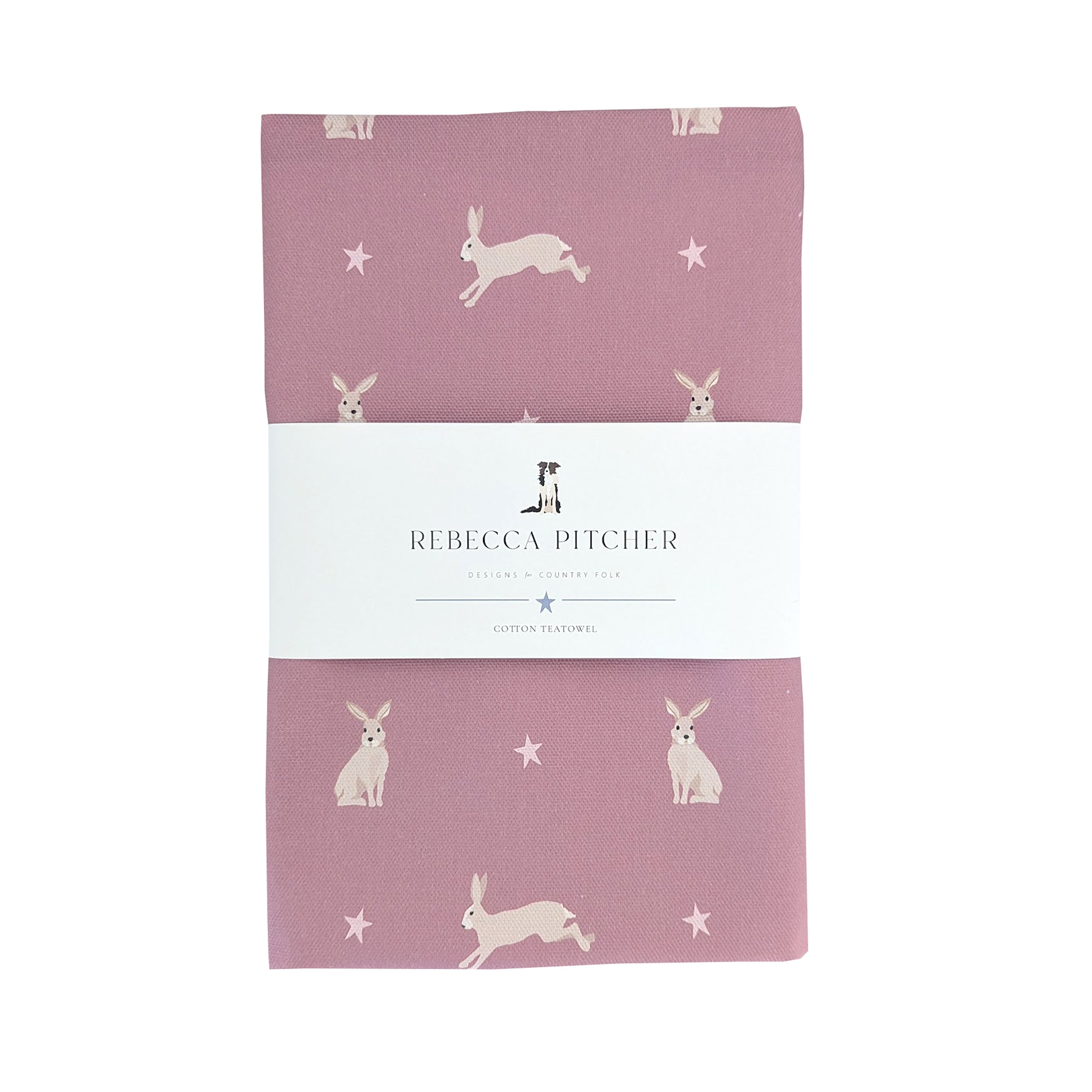 A pink cotton kitchen towel with hand-drawn hare designs, packaged with a white label displaying the brand name.