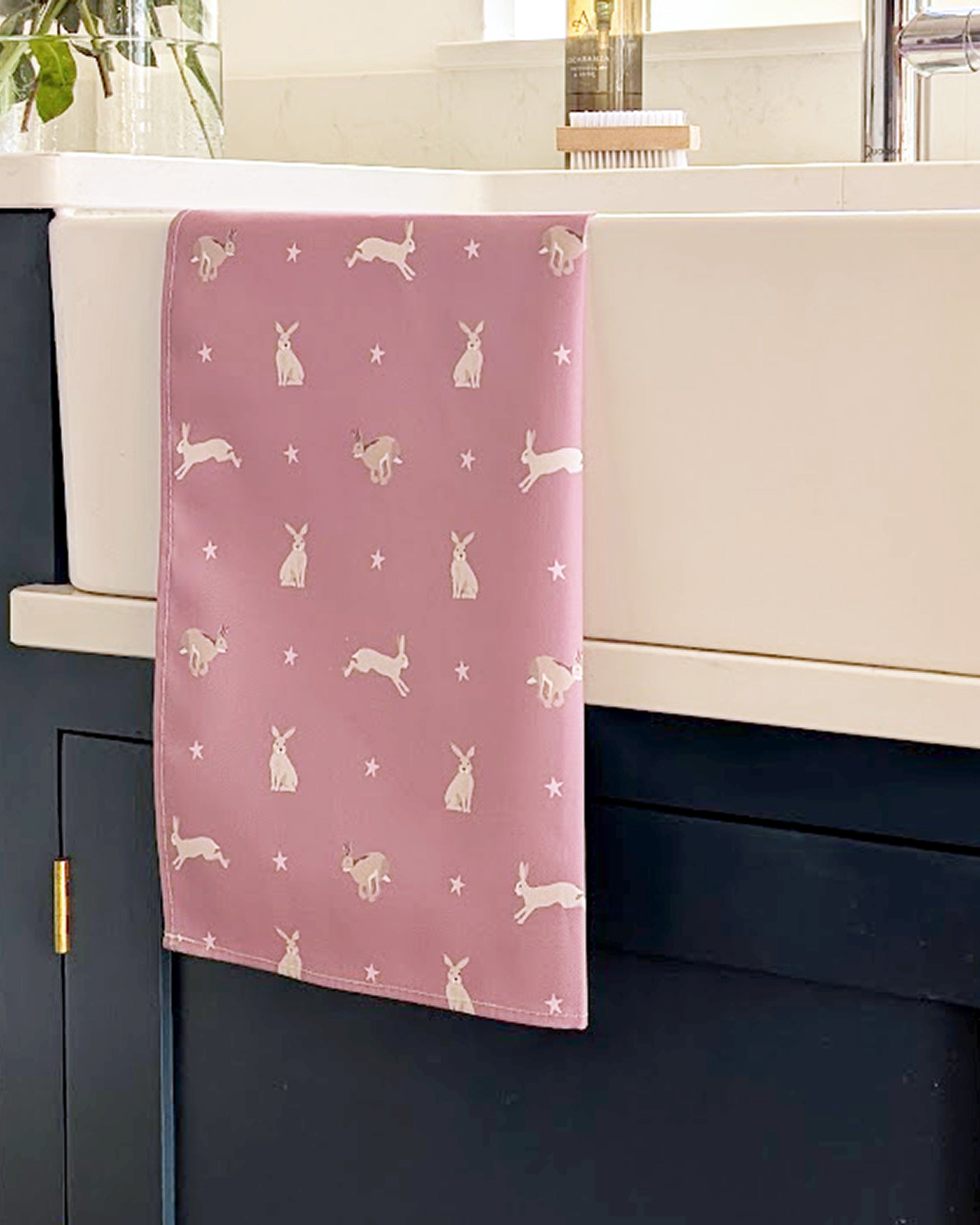 Pink towel with hare pattern hanging on a kitchen cabinet