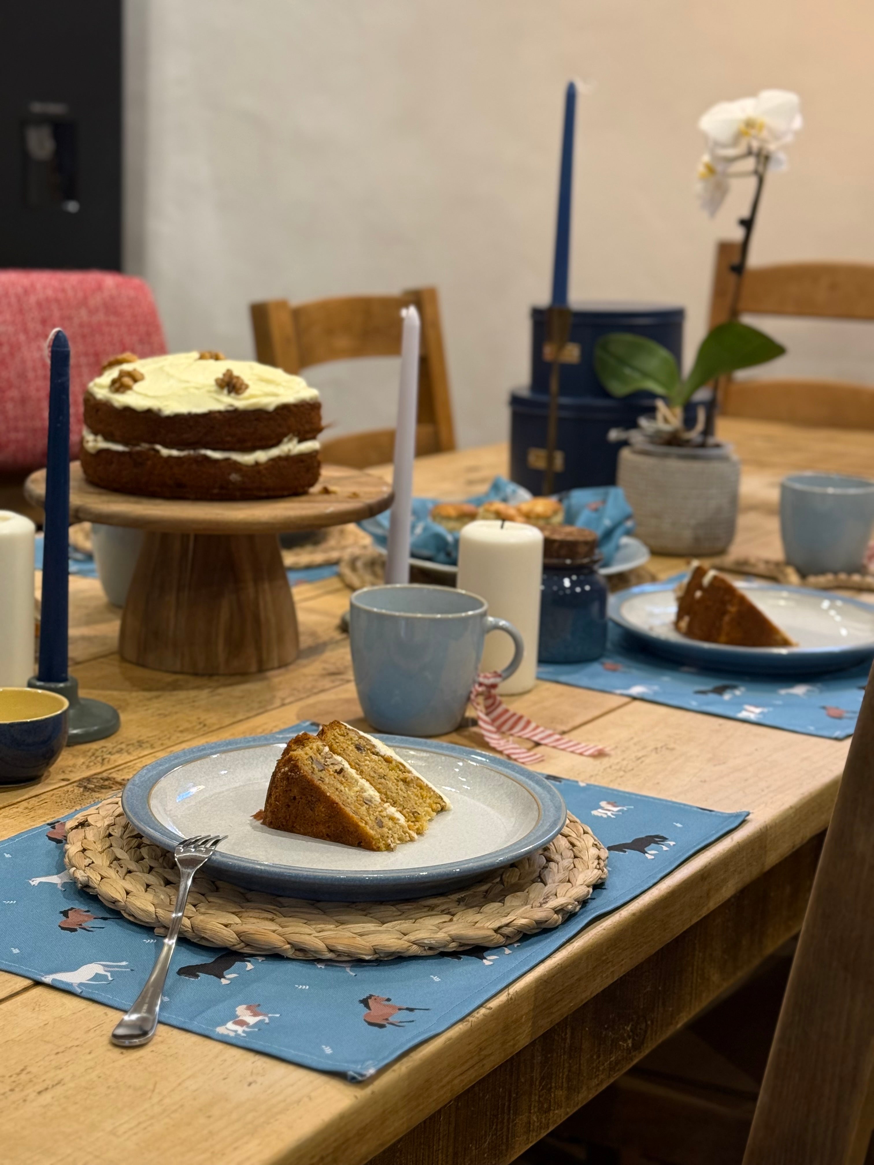 Dining table set with cake, coffee, and horse print table linens on a wooden table