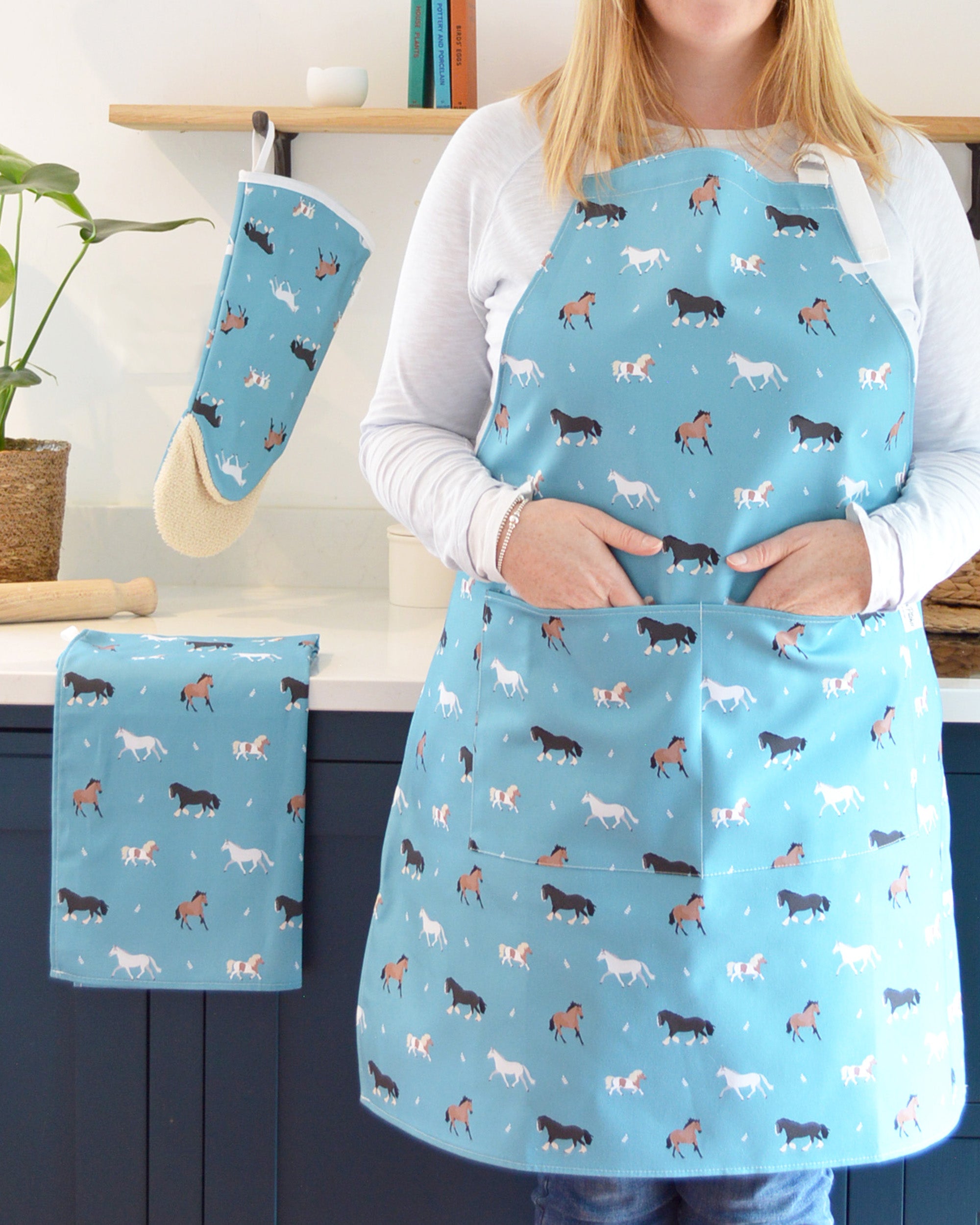 Rebecca Pitcher wearing a blue apron with horse pattern in a kitchen setting