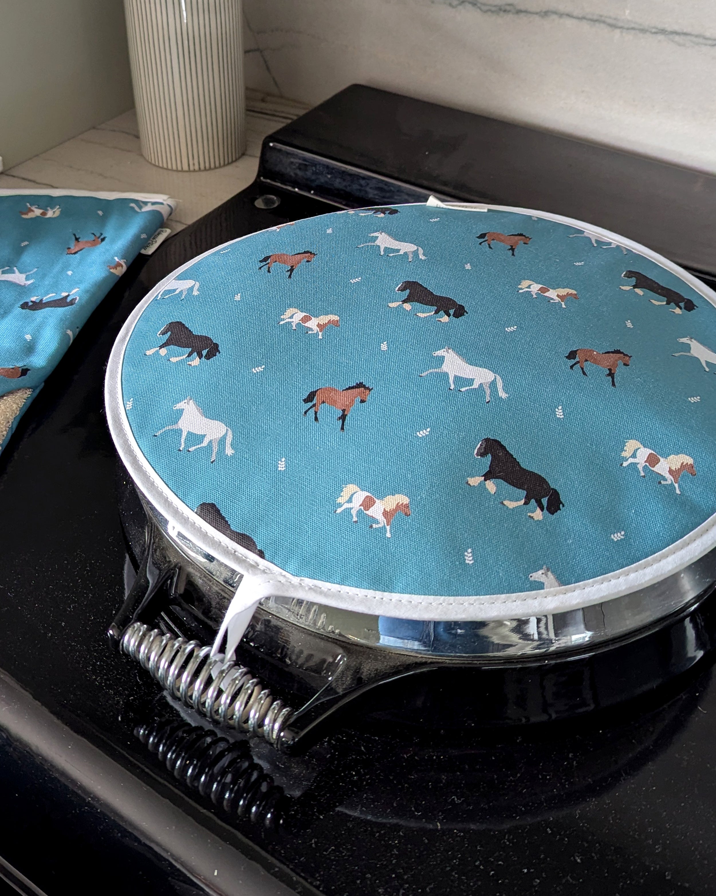 Round blue chef pad with horse pattern on a stovetop
