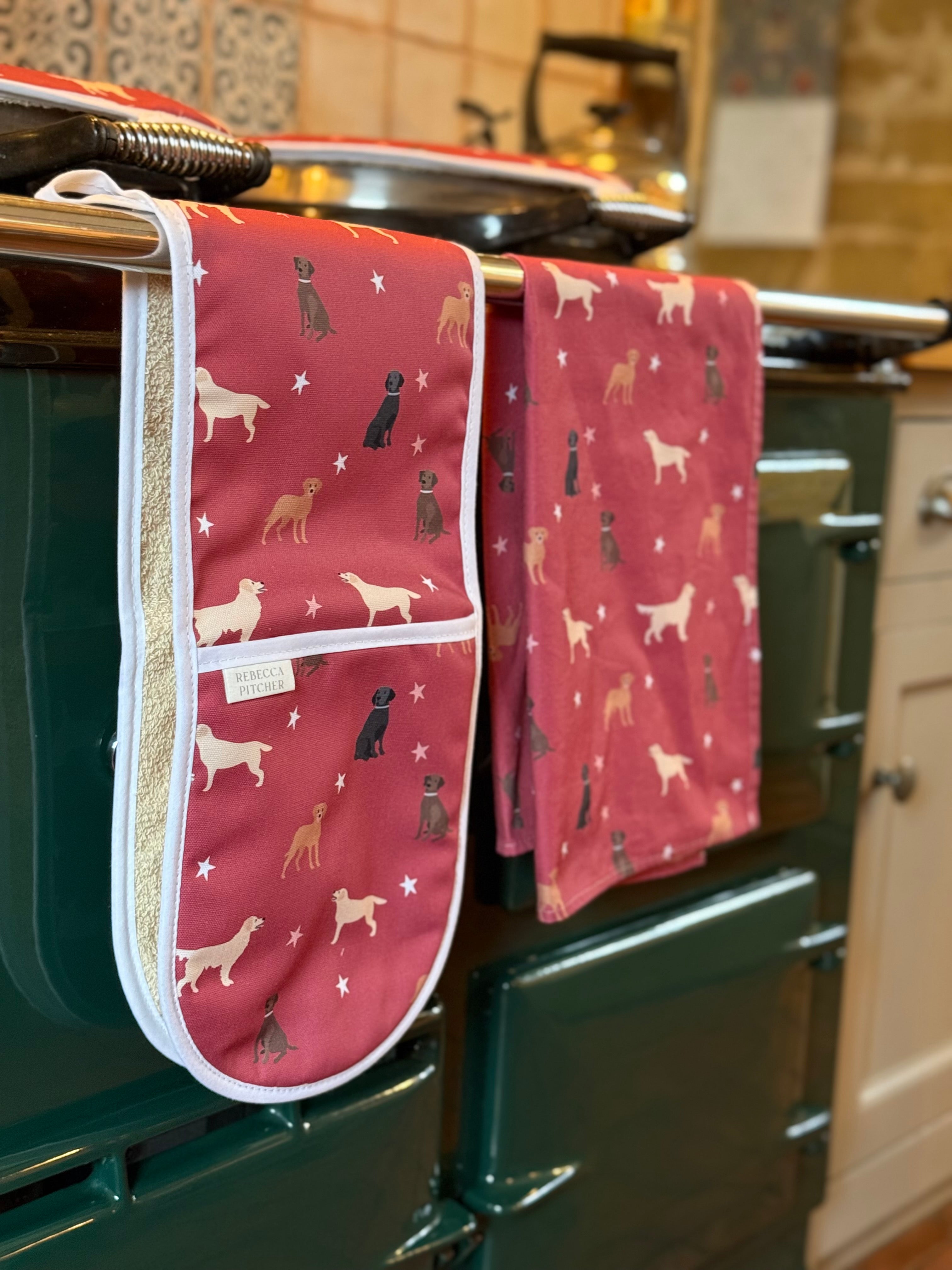 Red labrador dog print oven gloves, tea towel and hob covers hanging on a range cooker rail