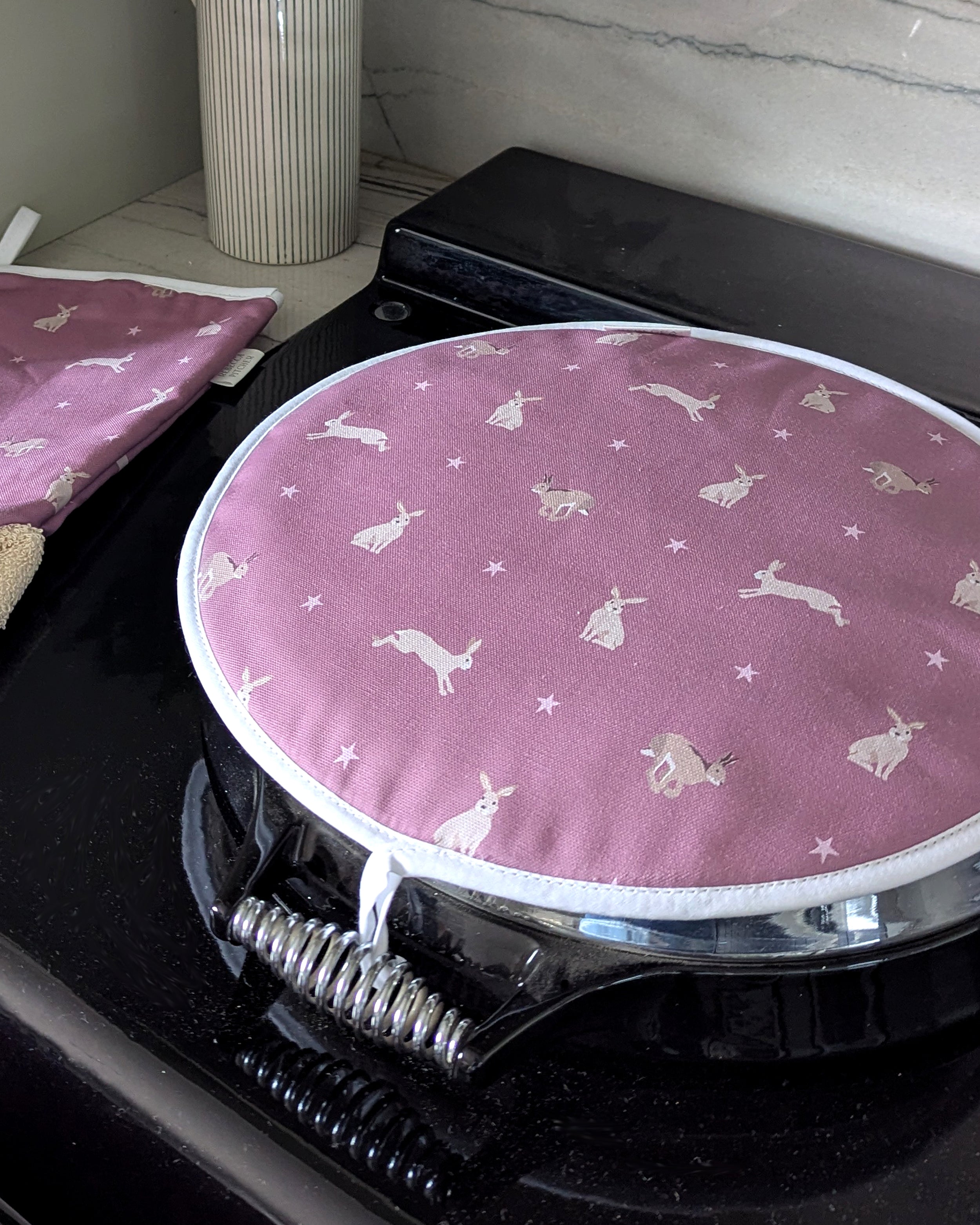 Pink hob cover with hare patterns on a range cooker