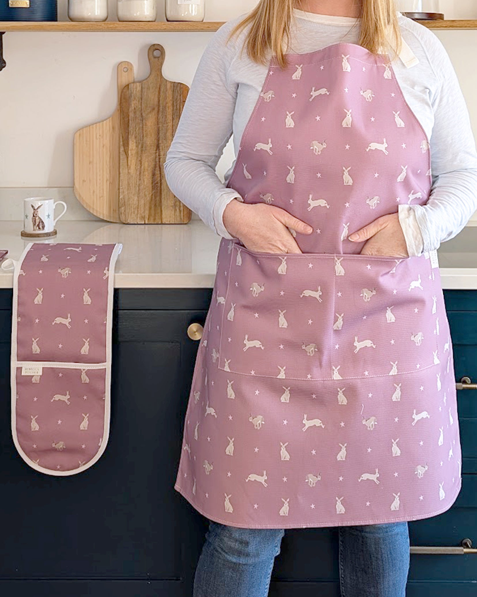 Rebecca Pitcher wearing a pink apron with hare patterns in a kitchen setting