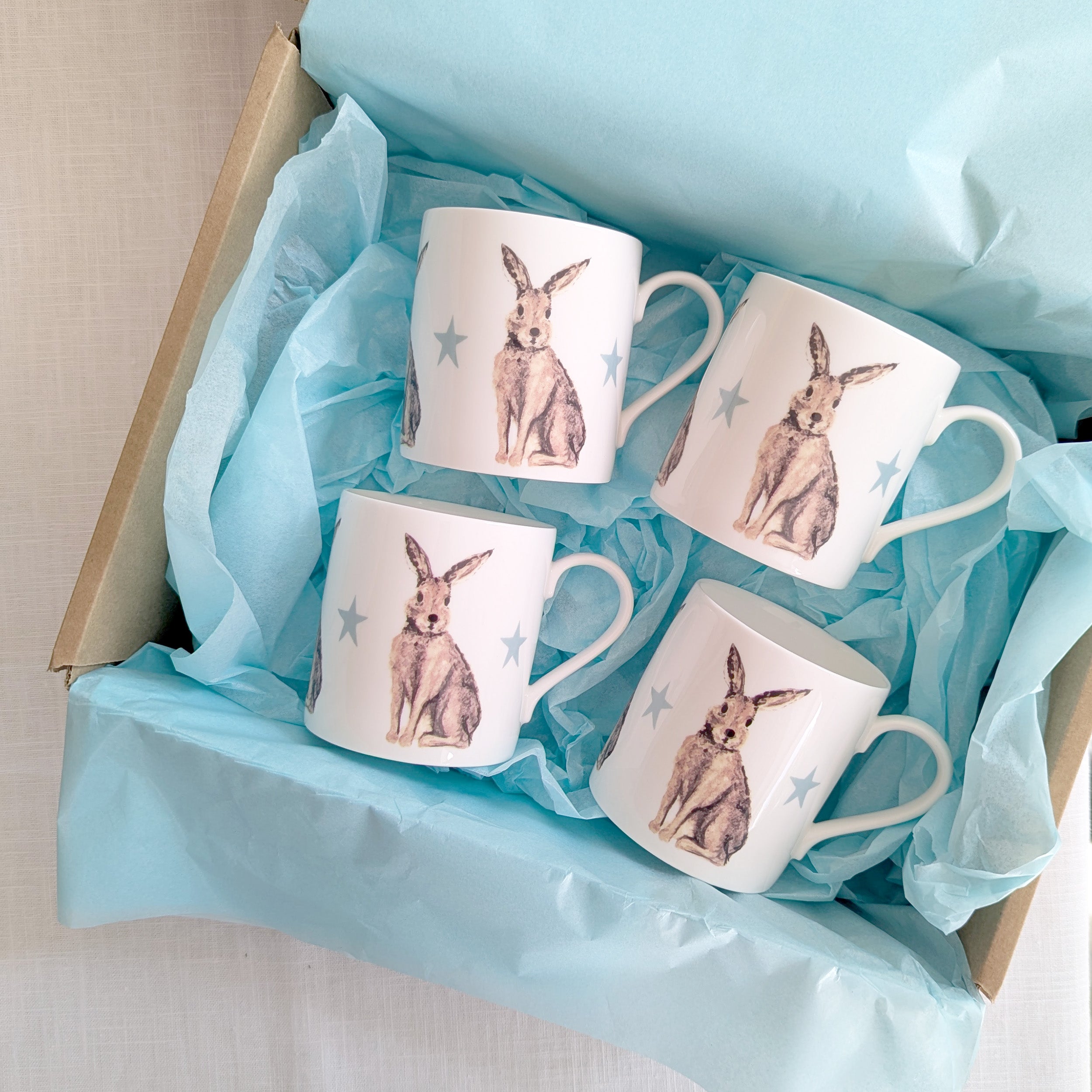 Four mugs with hare design in a box lined with blue tissue paper