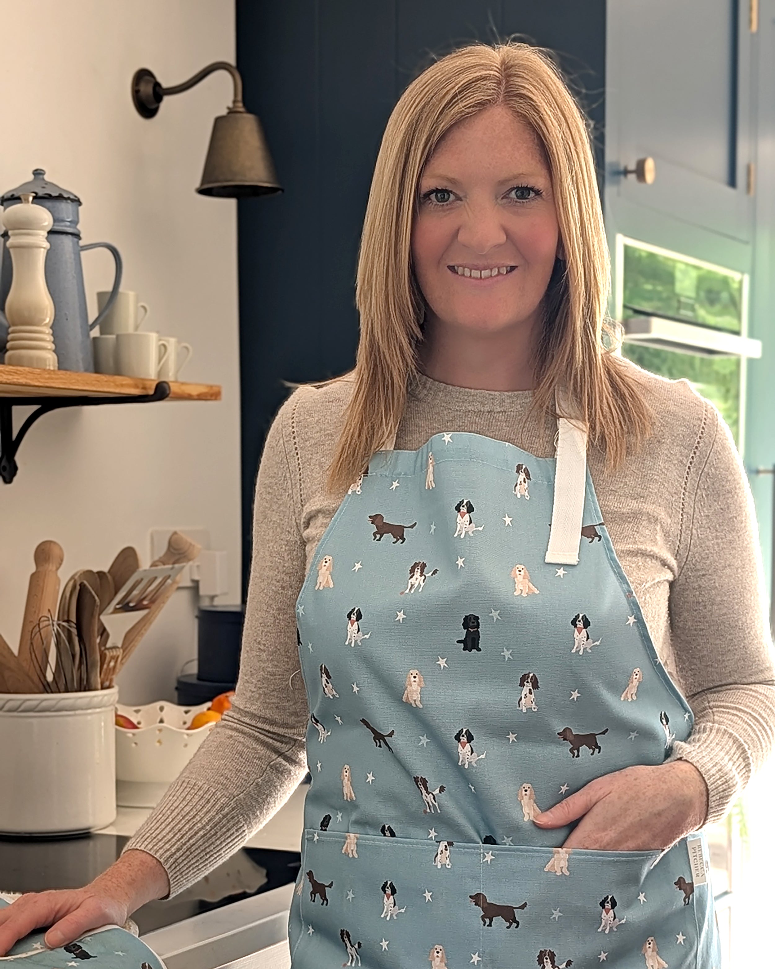 Woman wearing a blue apron with spaniel dog pattern in a kitchen