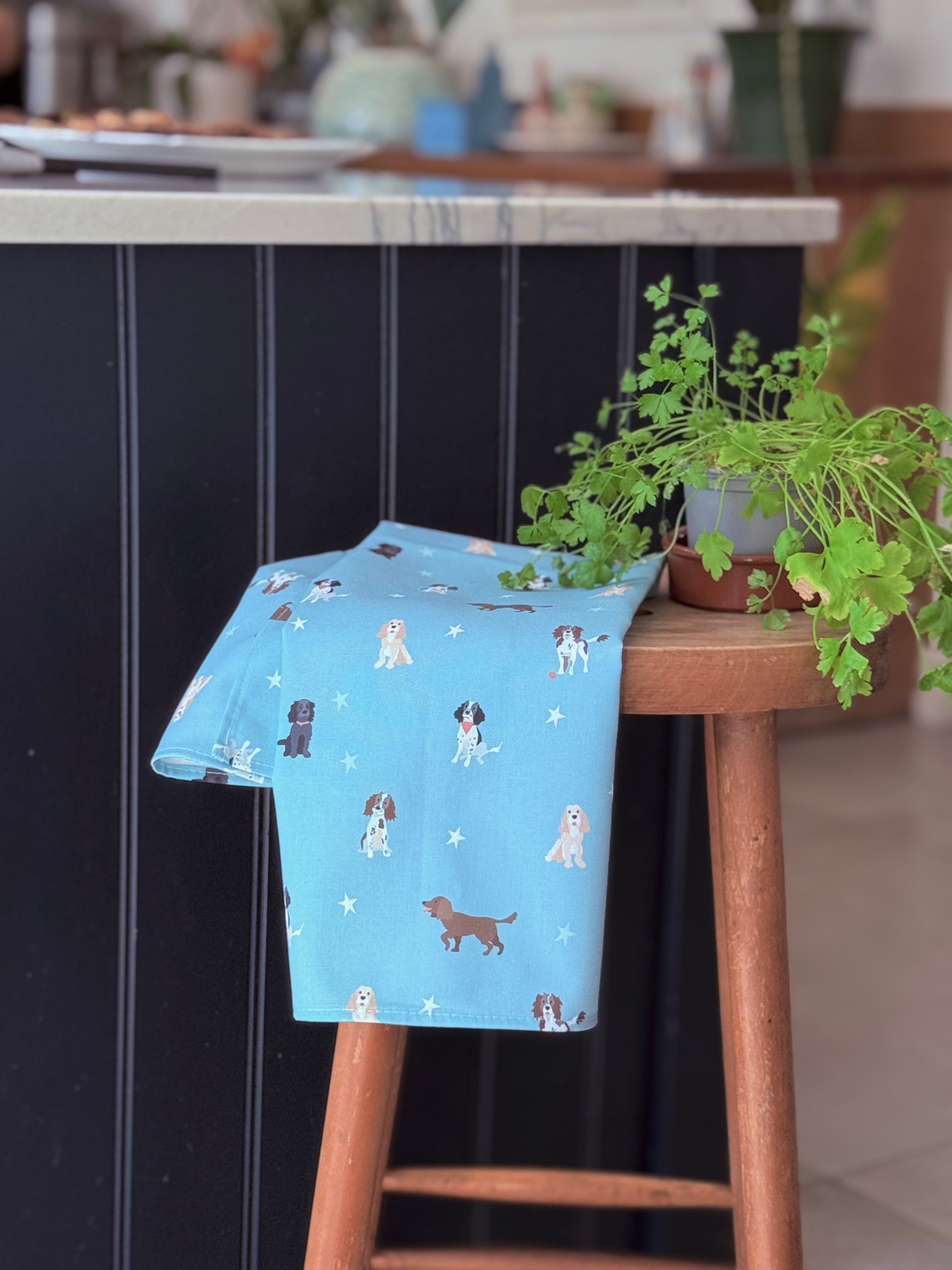 Blue tea towel with spaniel dog pattern on a wooden stool in a kitchen setting