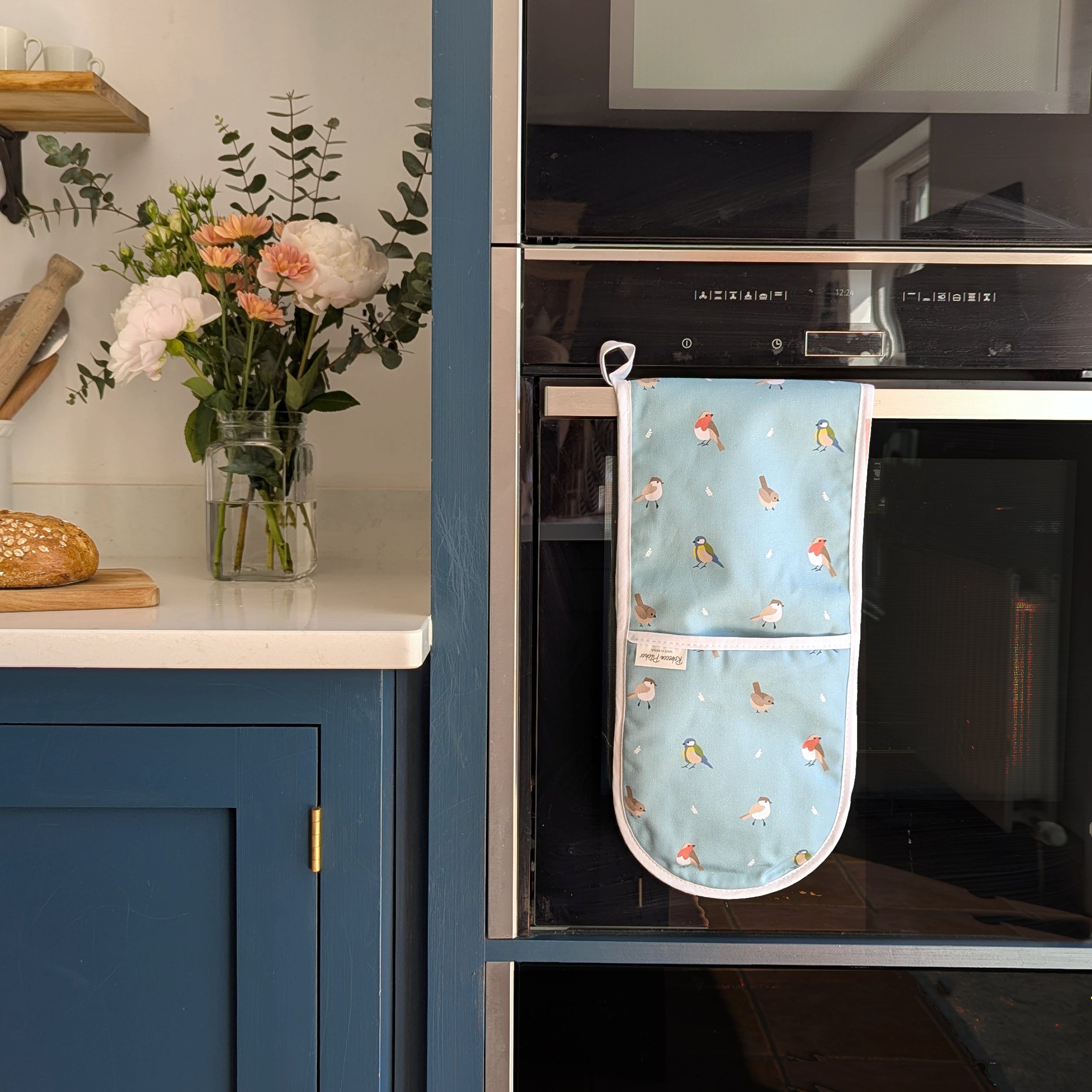 Teal Garden Bird design double oven gloves hanging on the oven handle