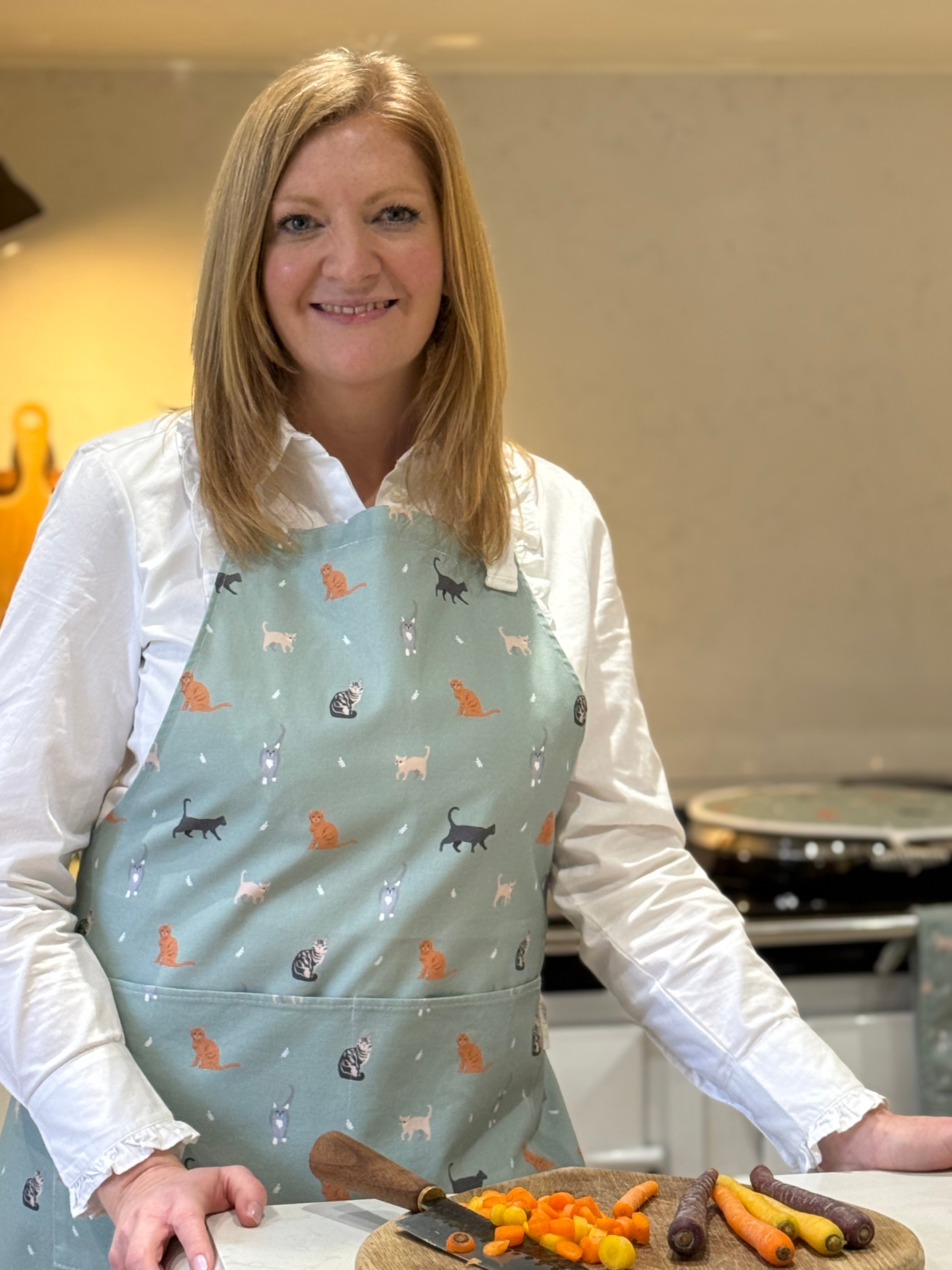 Woman wearing a green cats pattern apron in a kitchen setting