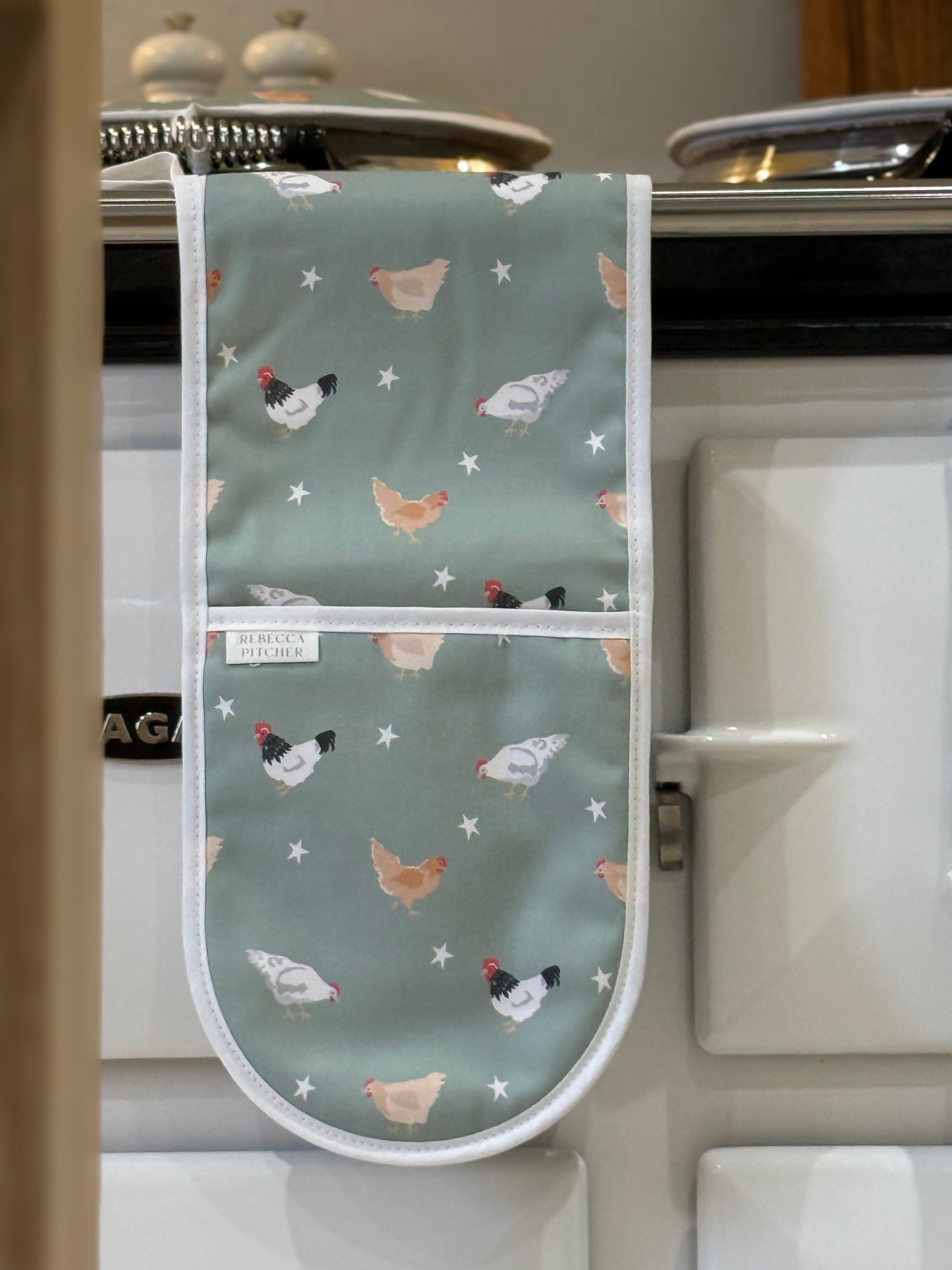 Oven glove with chicken pattern hanging on a stove