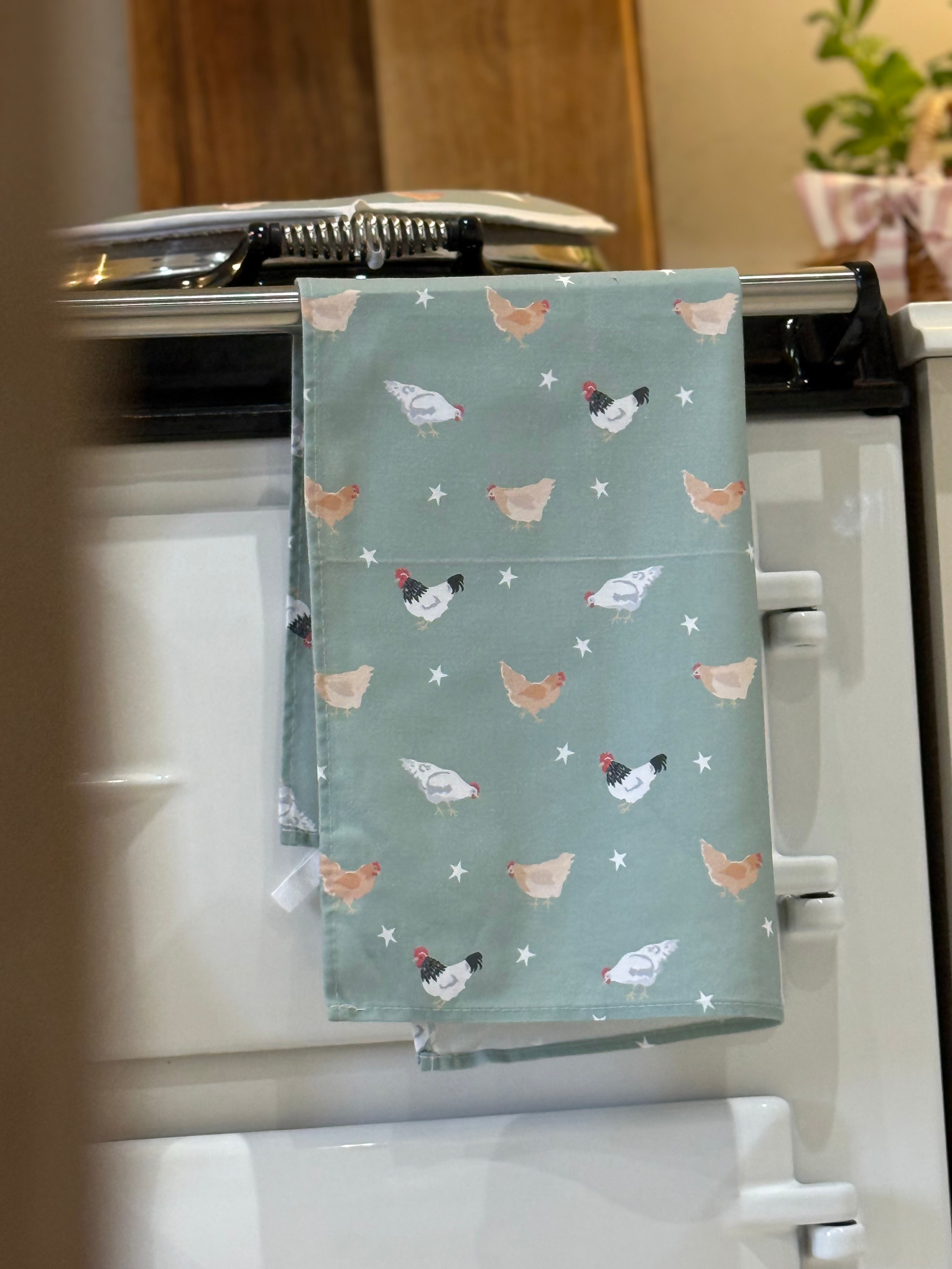 Green chicken pattern tea towel hanging on a country style stove