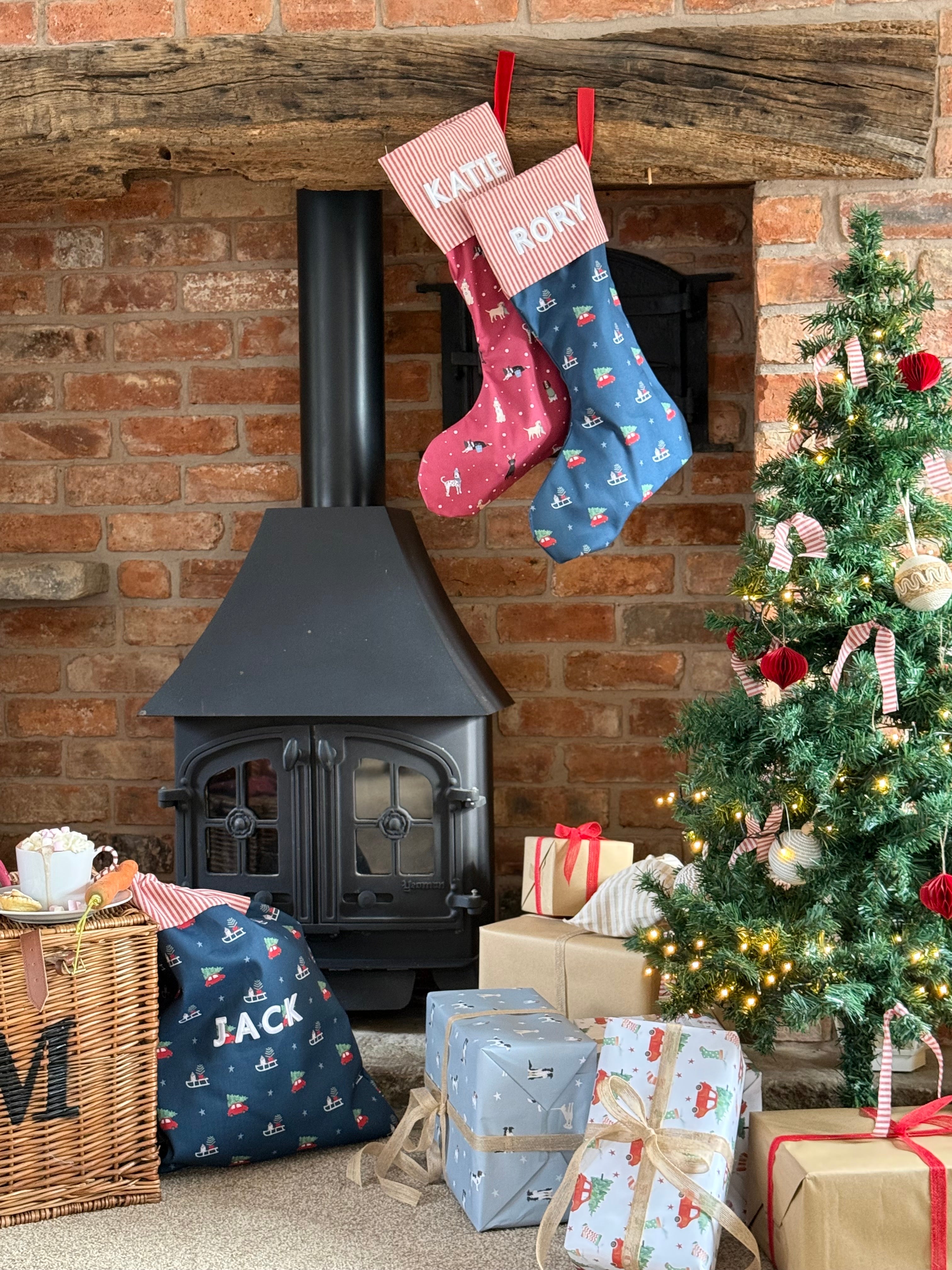 Christmas stockings hanging above a fireplace with a decorated Christmas tree and presents.