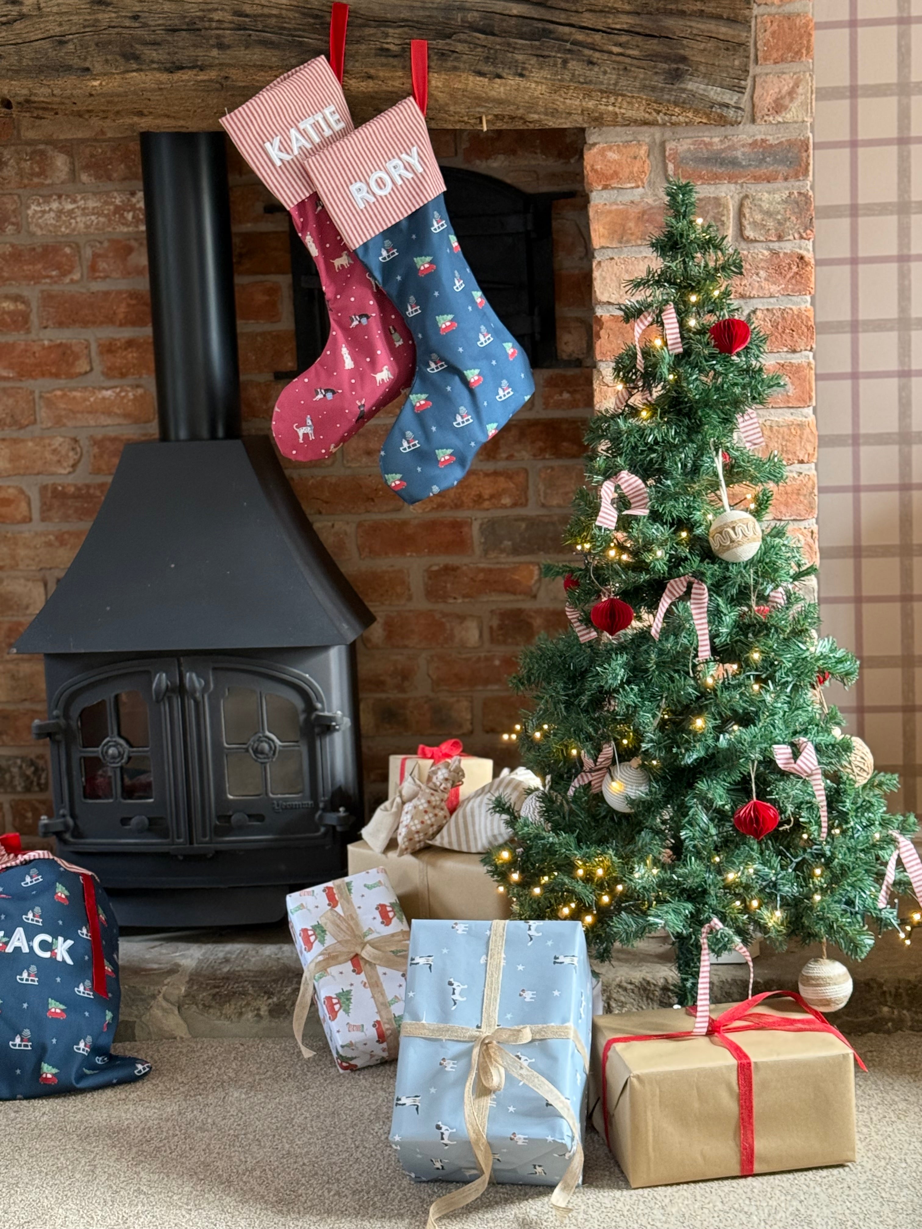 Christmas scene with stockings hanging above a fireplace, decorated tree, and presents.