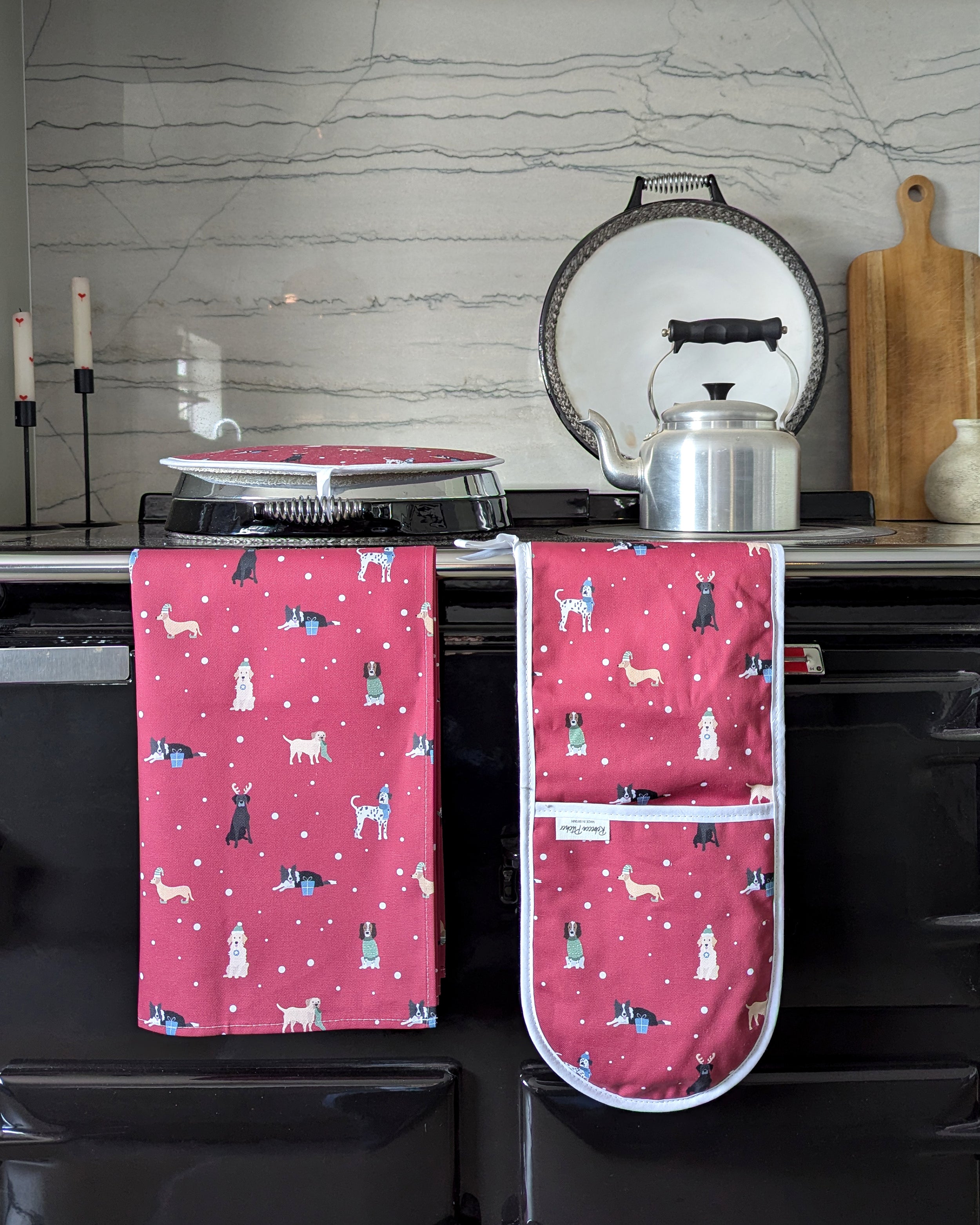 Red kitchen textiles with Christmas dog pattern hanging on a stove in a kitchen setting
