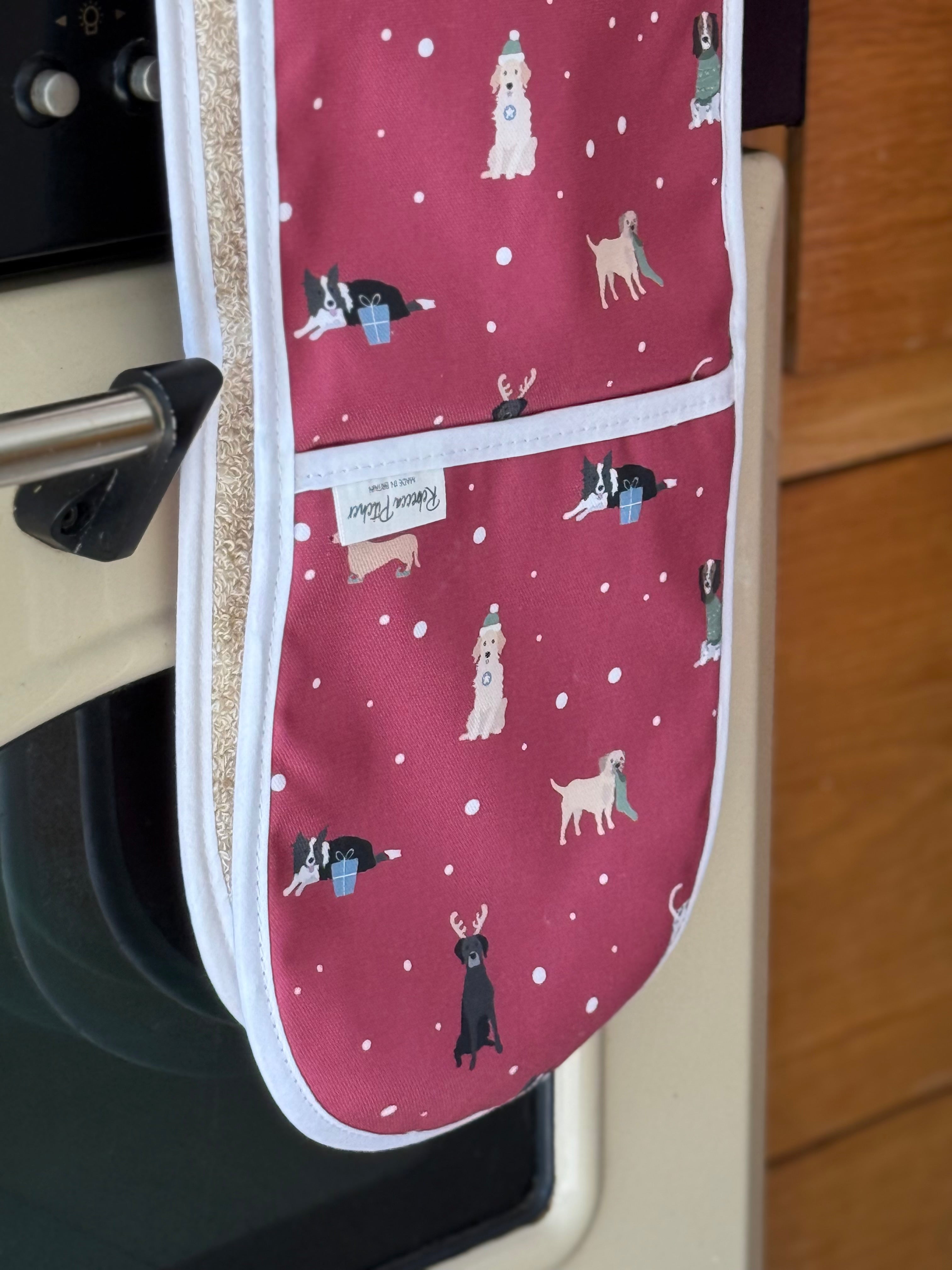 Red Christmas Oven Gloves with dog pattern on a kitchen oven