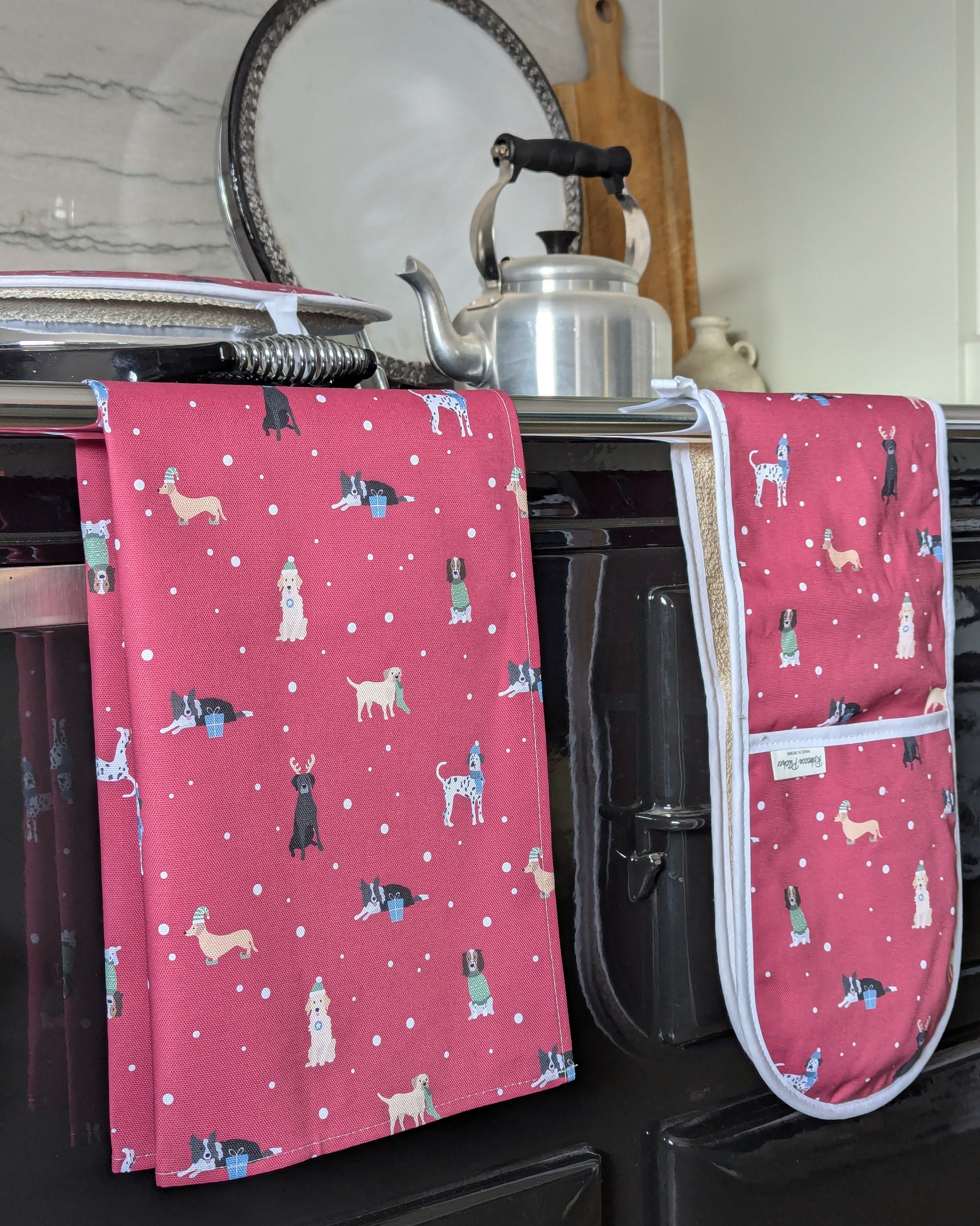 Red kitchen towel and oven mitts with Christmas dogs pattern on a kitchen range cooker