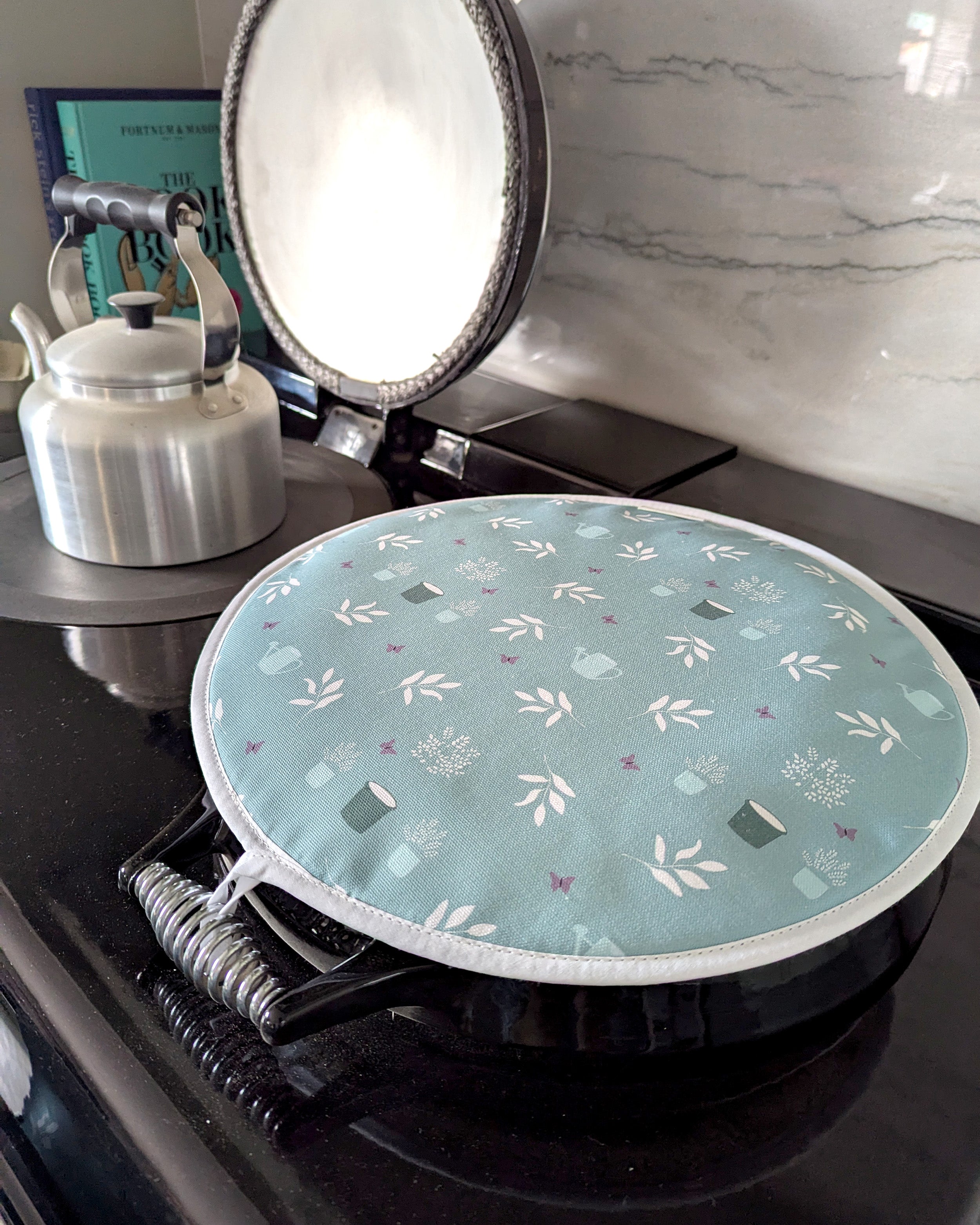 Round hob cover with floral pattern on a stove