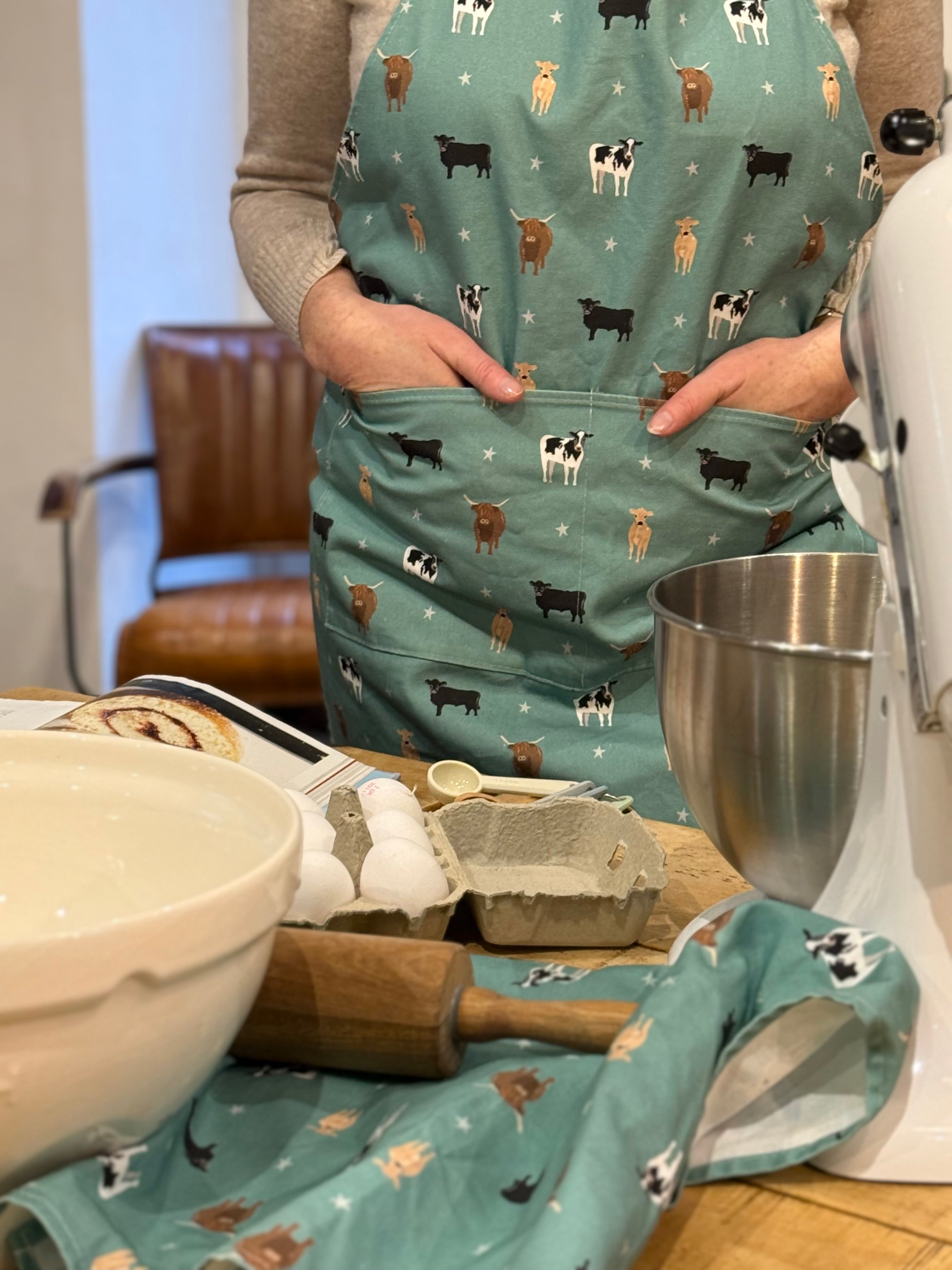 Person wearing a green apron with cow pattern in a kitchen setting