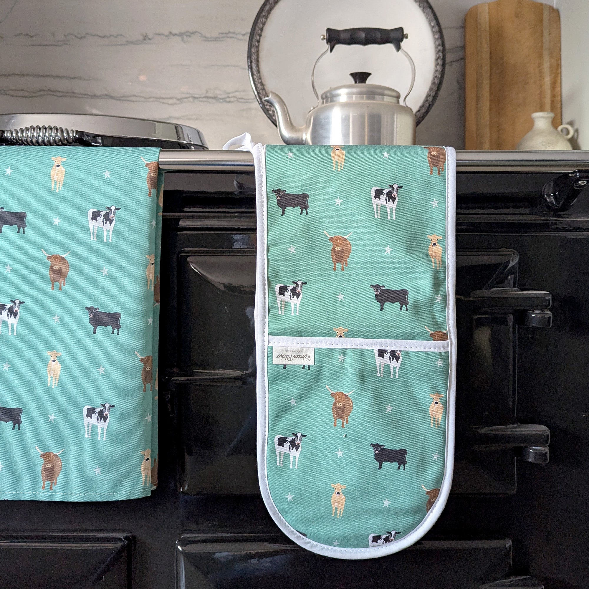 Green Cows Oven Gloves on a cooker rail