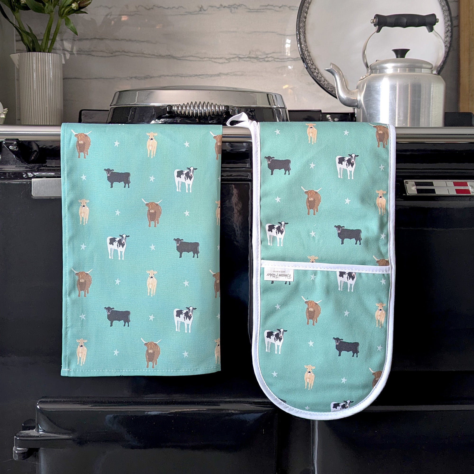 Green Cows Tea Towel and Oven Gloves on a cooker rail