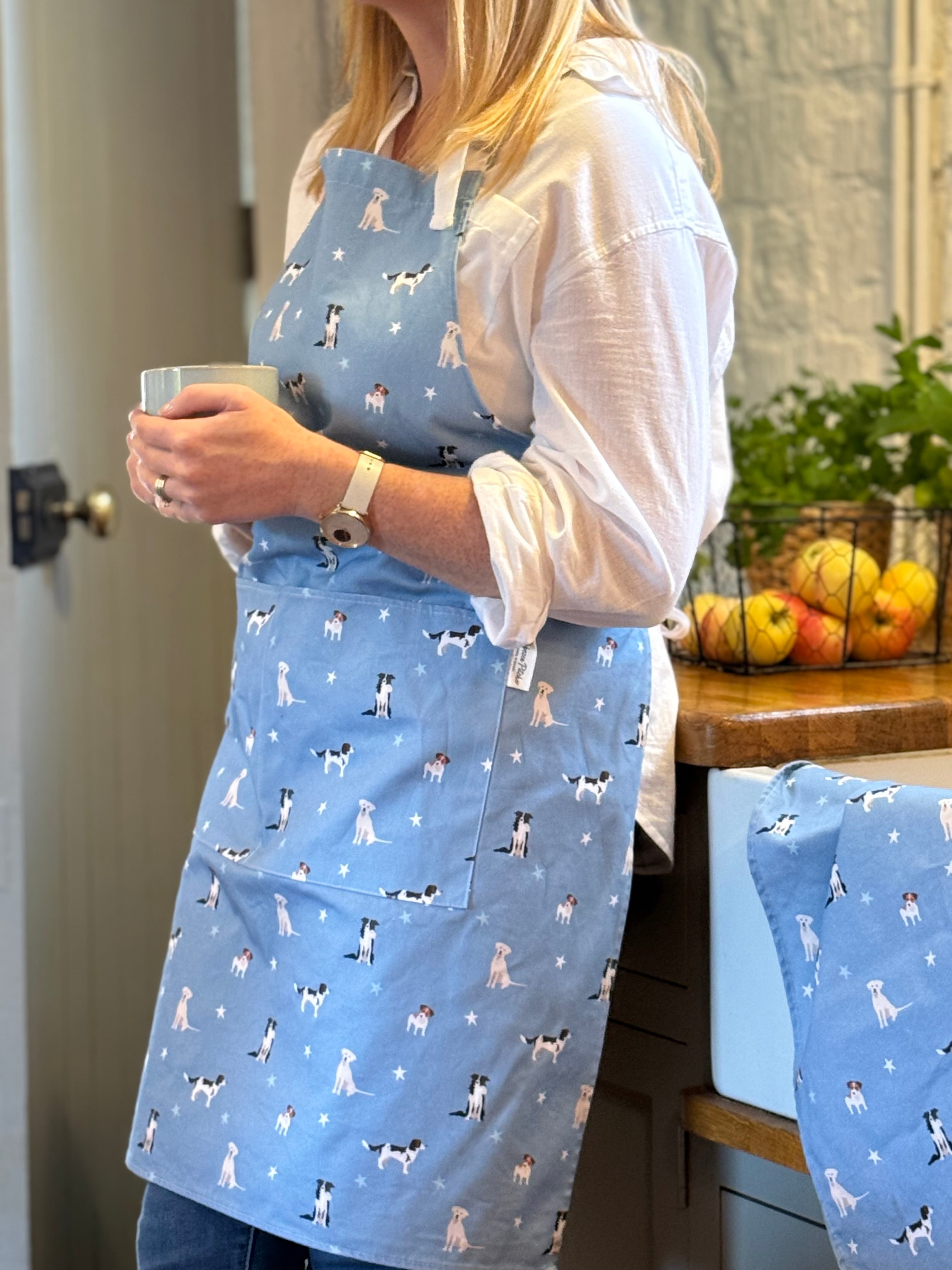 Person wearing a blue apron with dog pattern in a kitchen setting