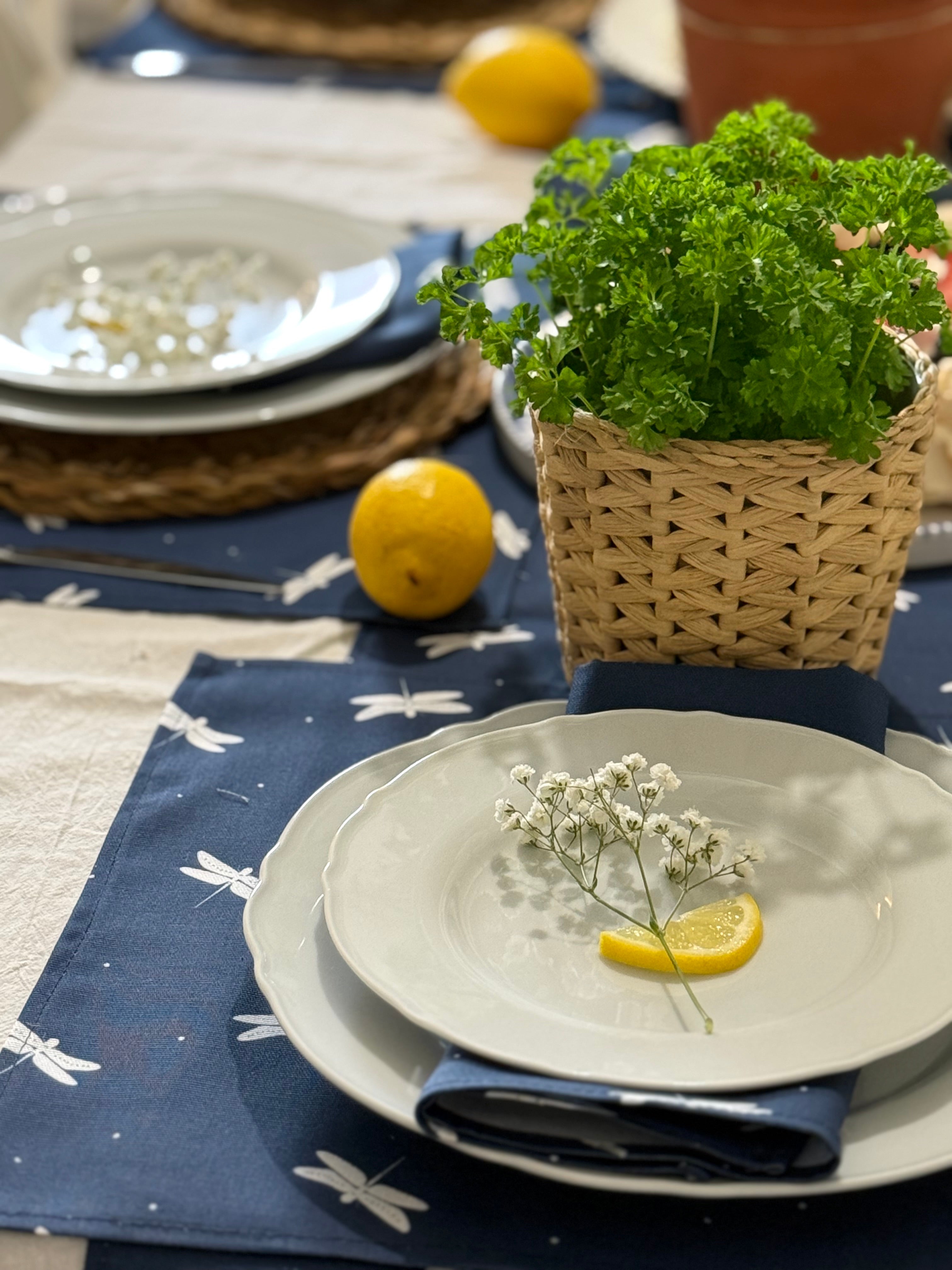 Table setting with plates, lemons, and a plant on a blue dragonfly pattern placemat