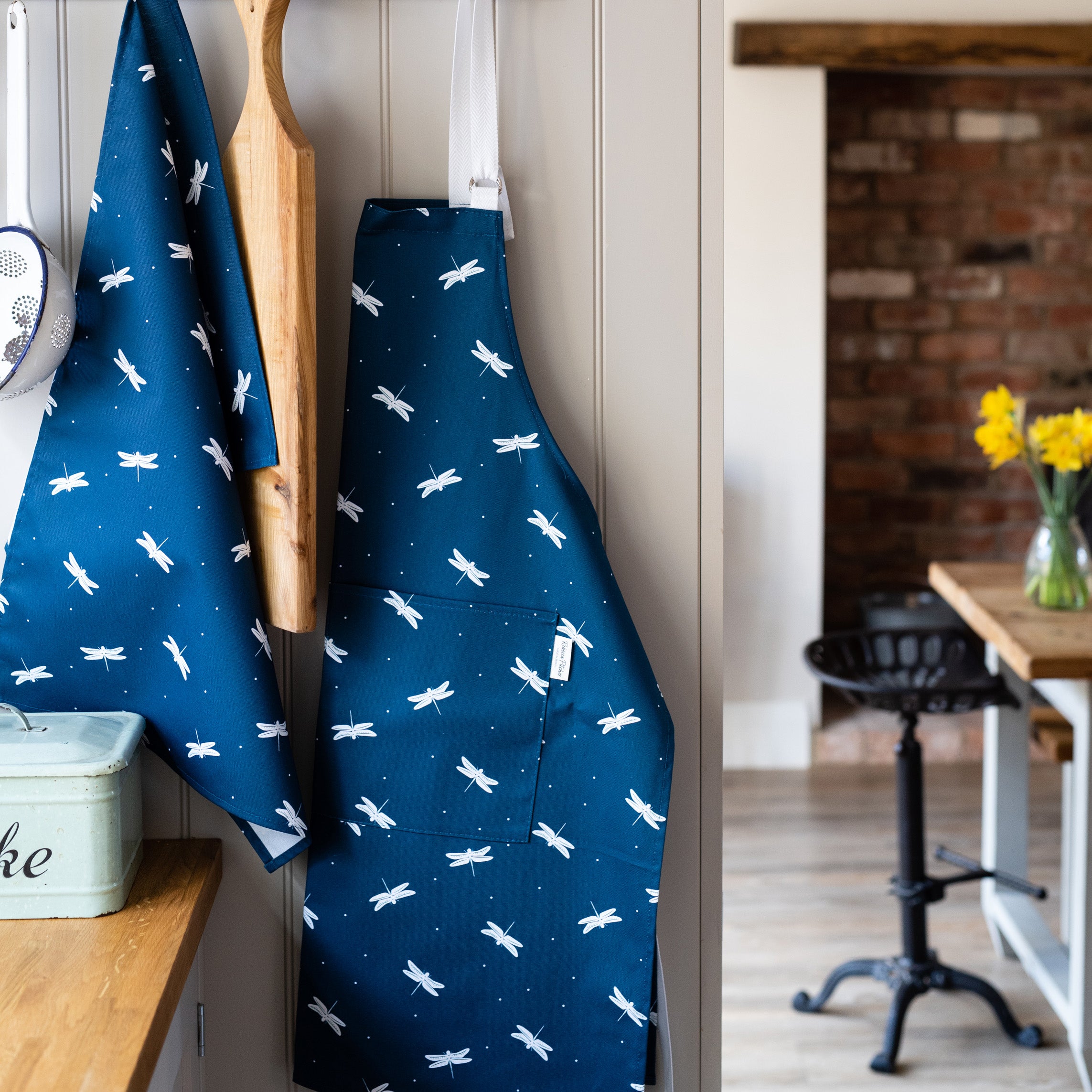 Navy Dragonfly apron and tea towel hanging in a kitchen