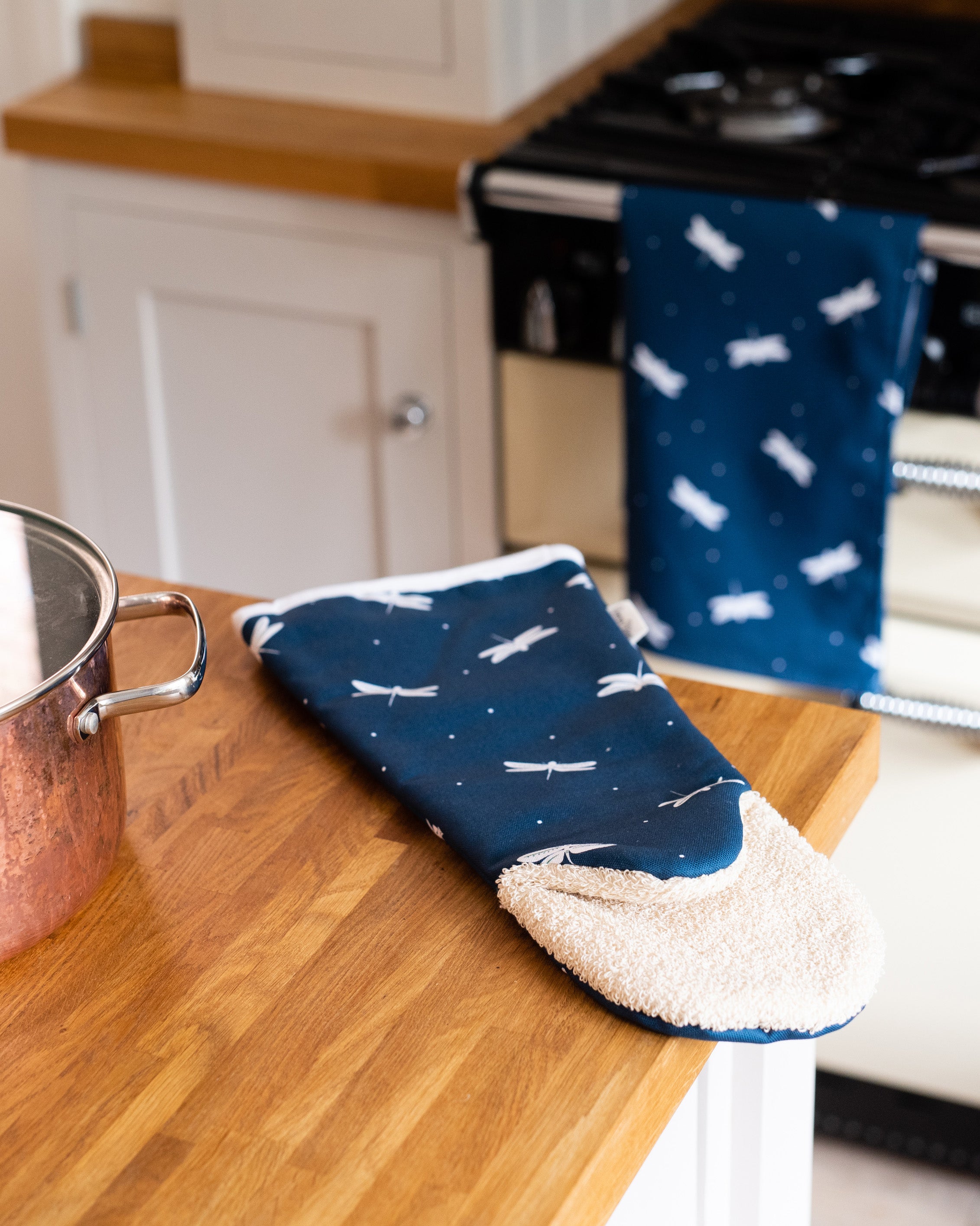 Blue oven gauntlet with white patterns on a wooden kitchen counter