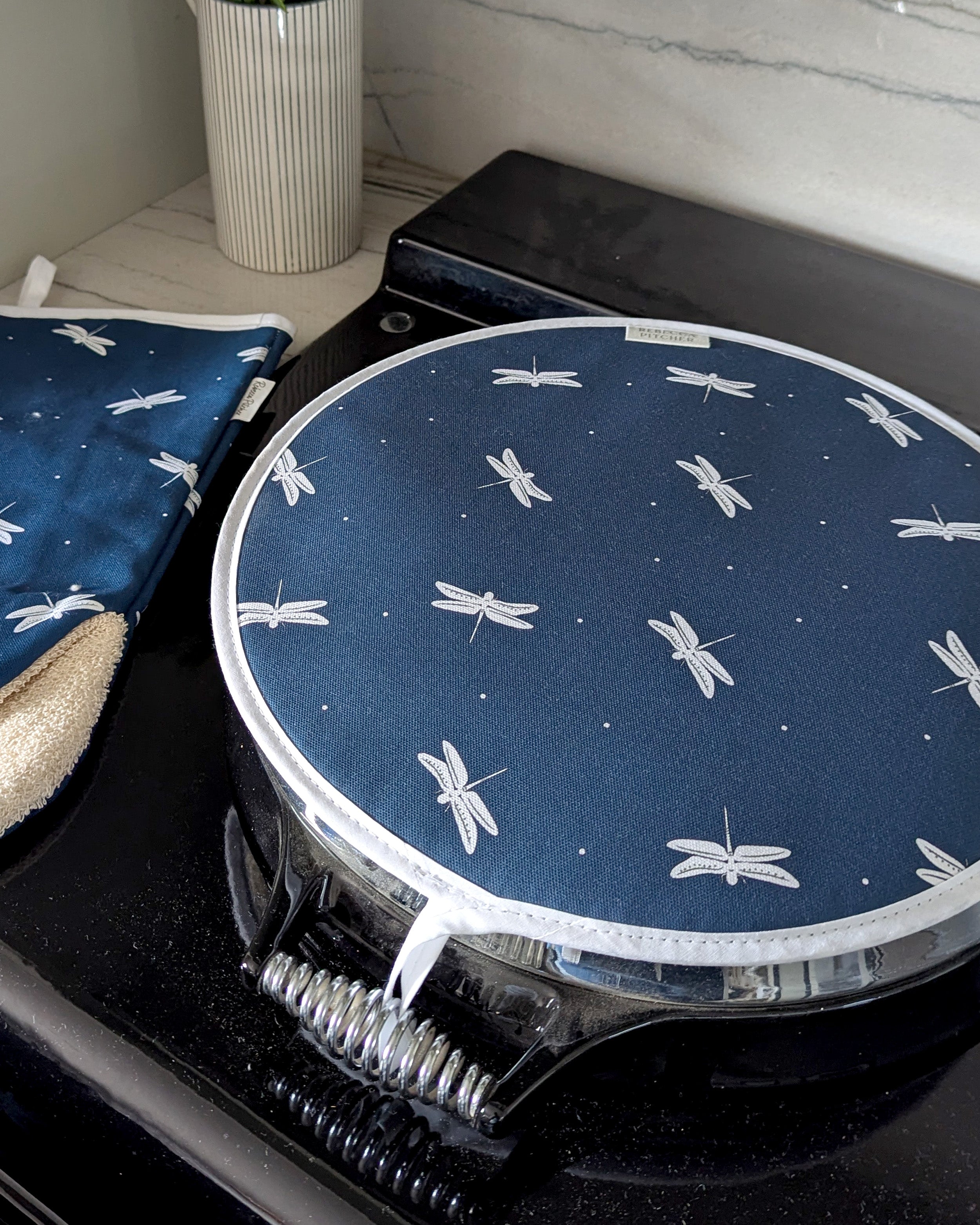 Navy blue hob cover with white dragonfly pattern on a stove