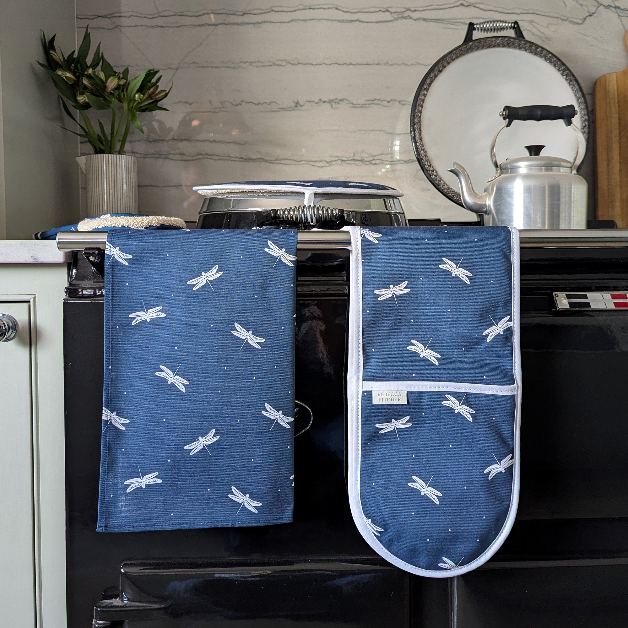 Navy blue dragonfly tea towel and oven gloves on a cooker rail