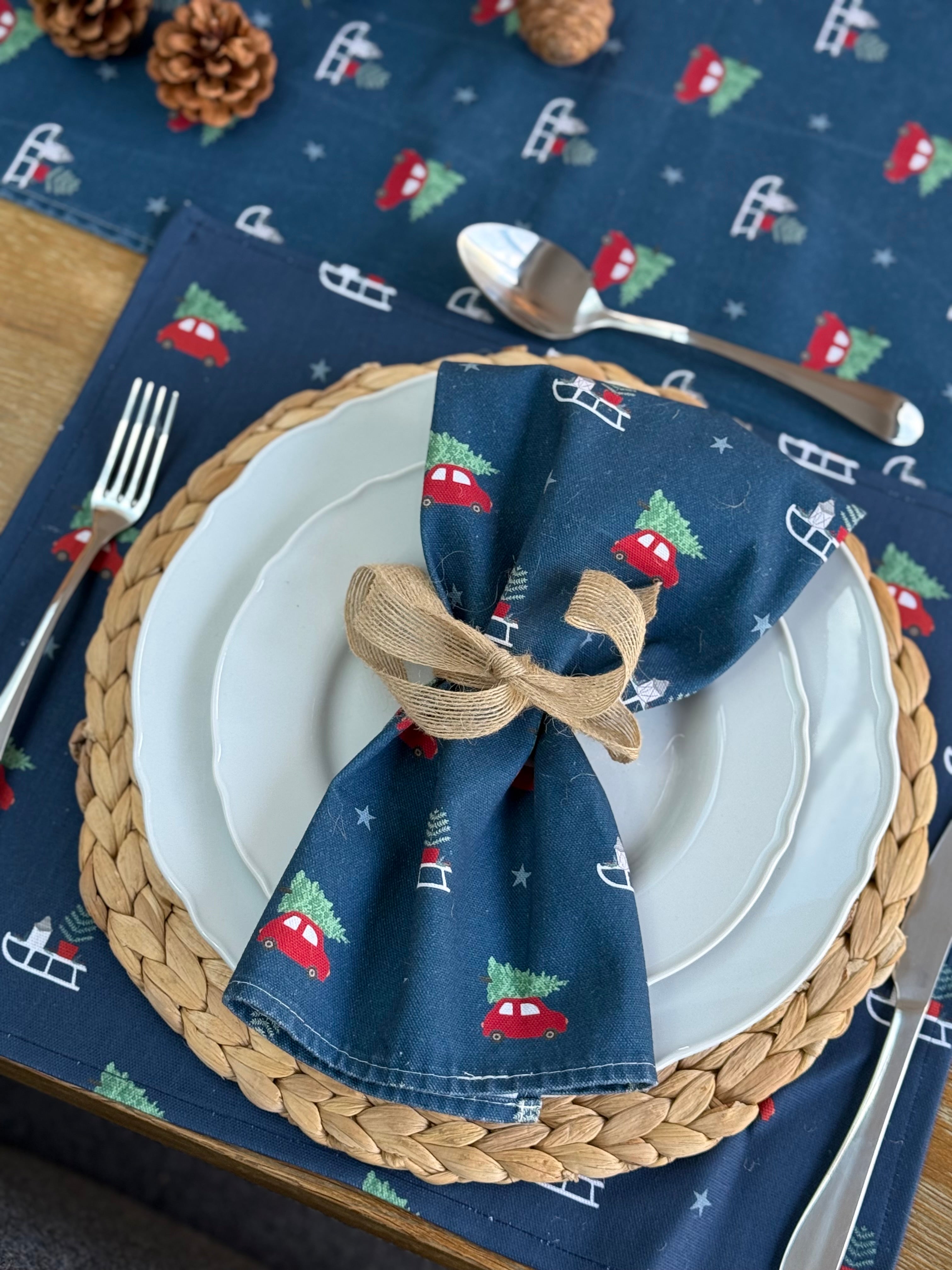 Napkin with Christmas design on a plate with cutlery on a festive tablecloth.