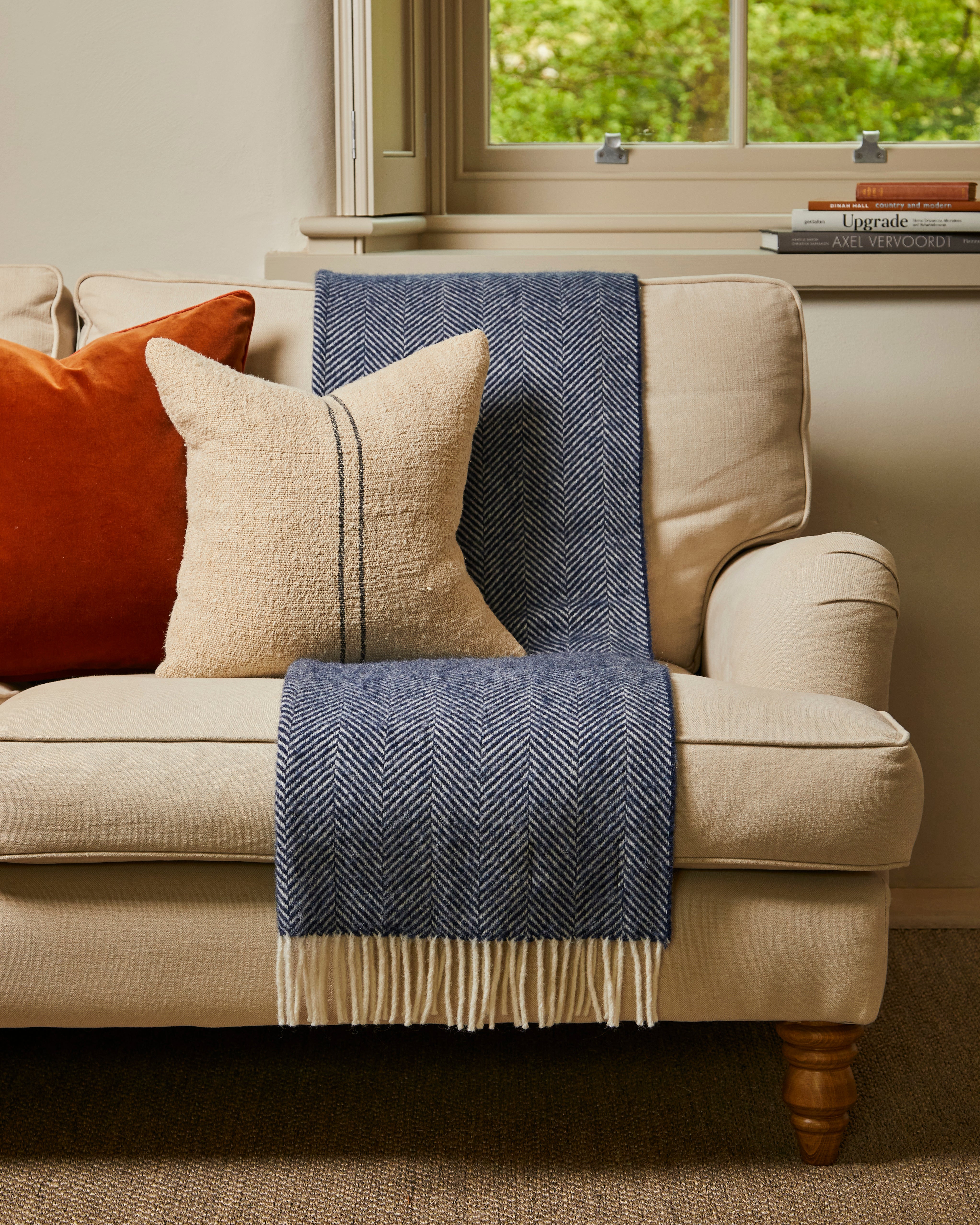 Navy Fishbone Wool Blanket on a cream sofa with cushions