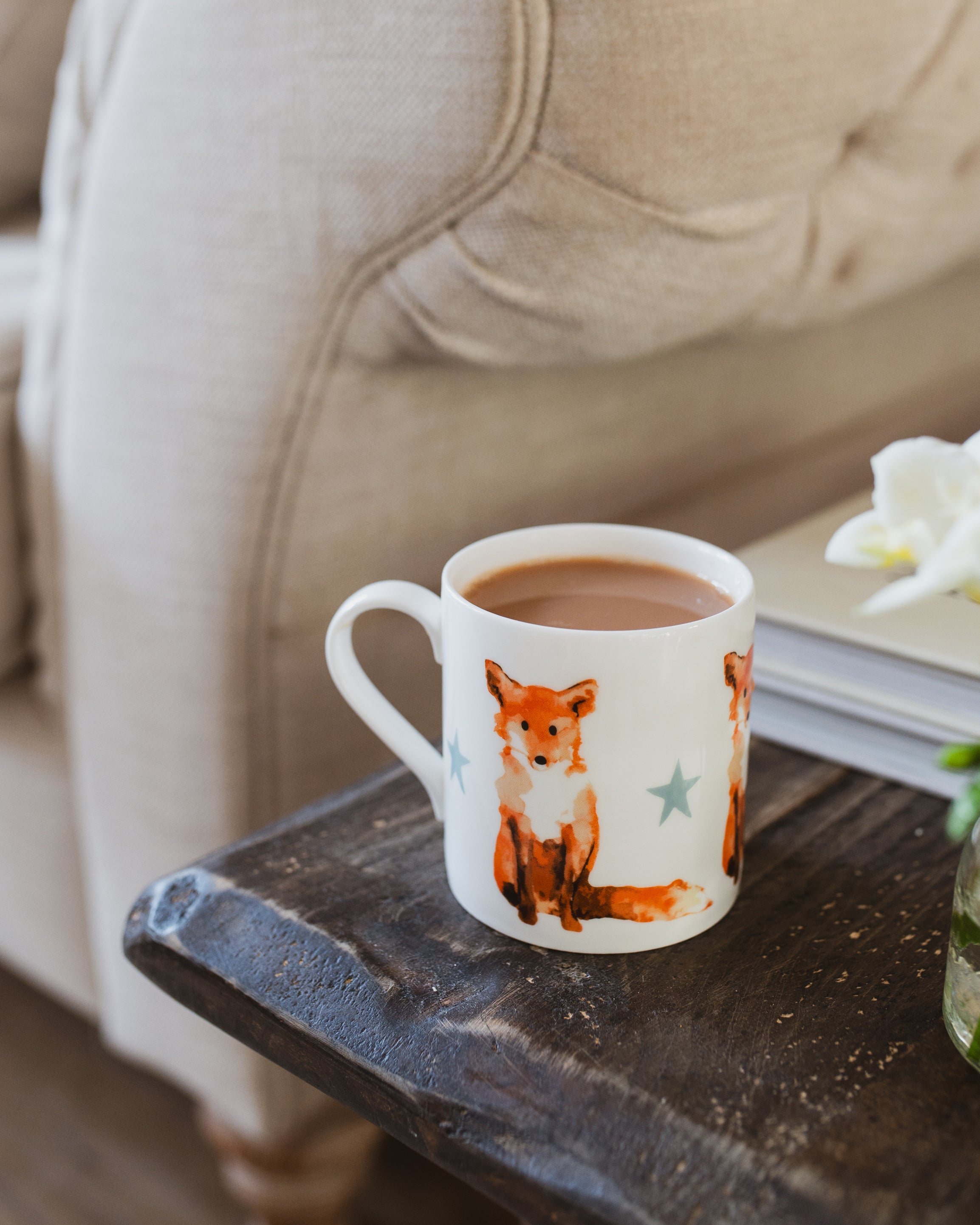 Mug with a fox design on a wooden table next to a sofa