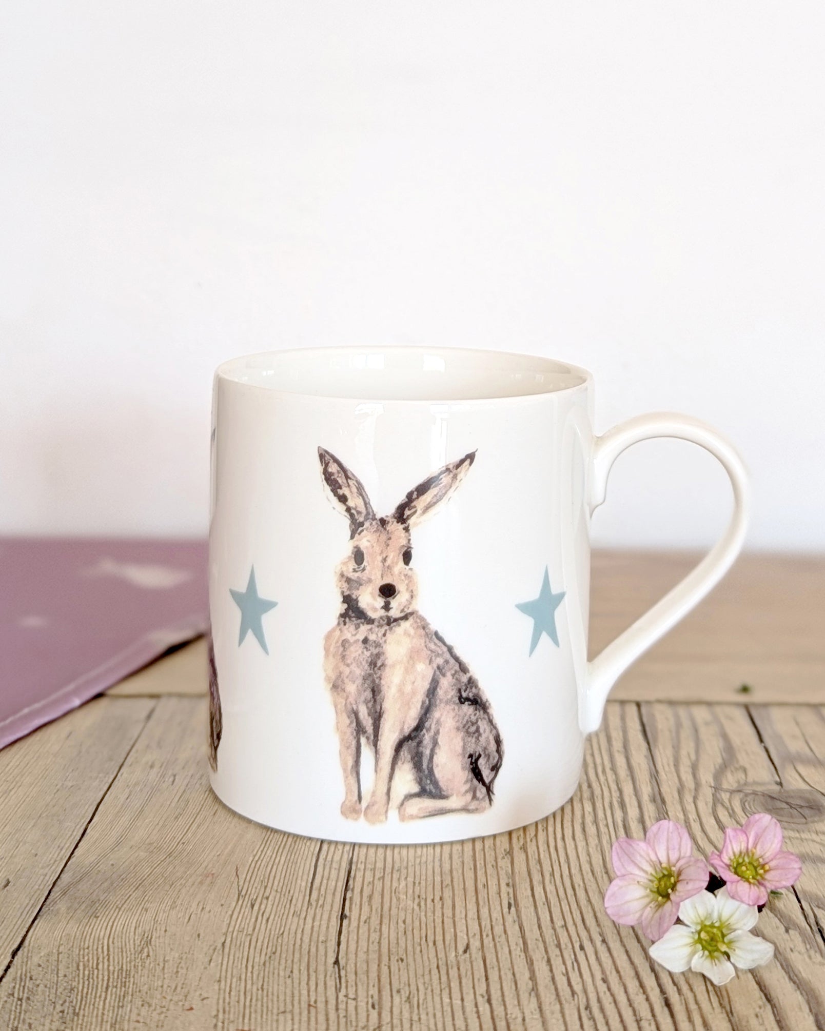 China mug with a hare illustration on a wooden surface with flowers